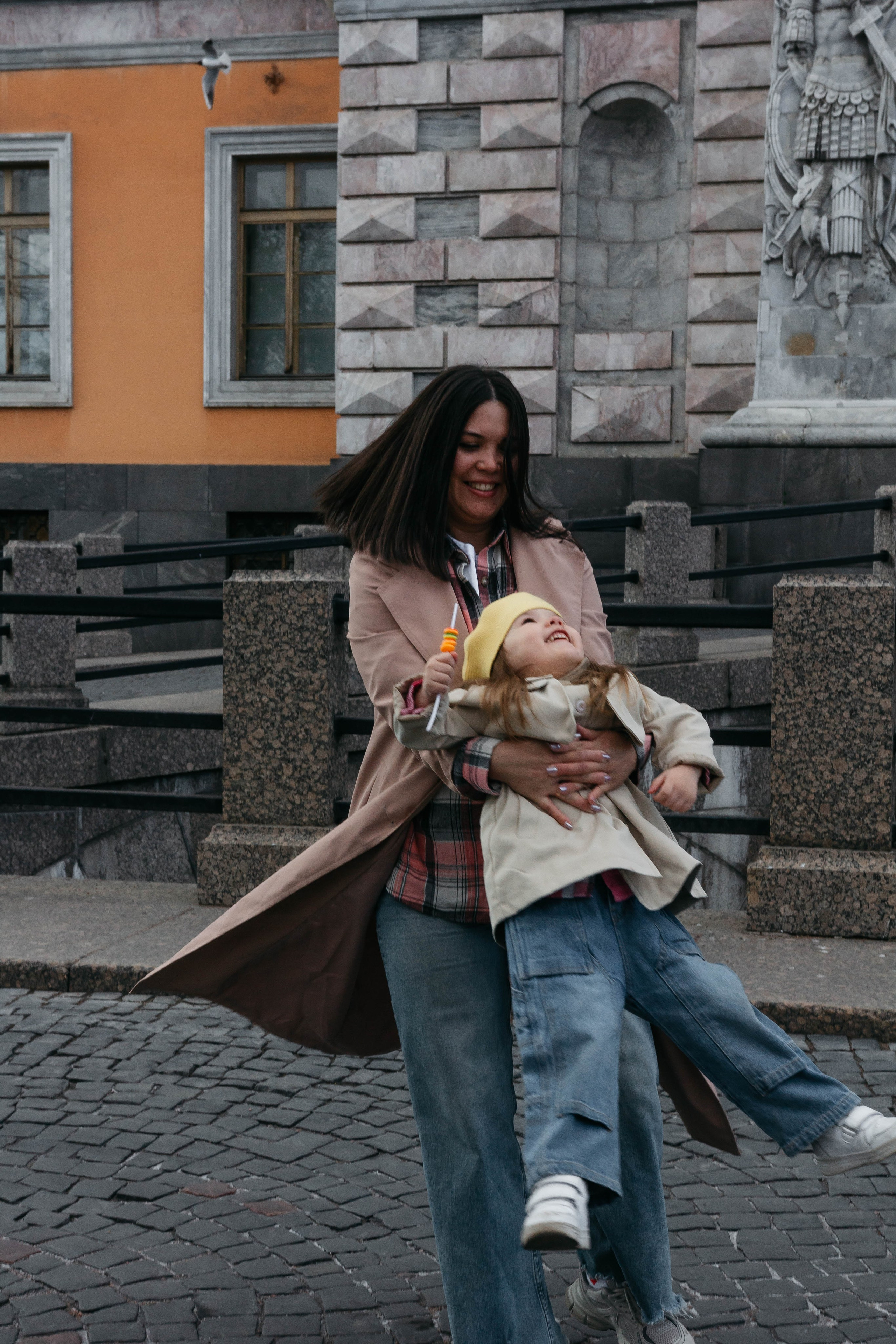 мама кружит ребенка на прогулке