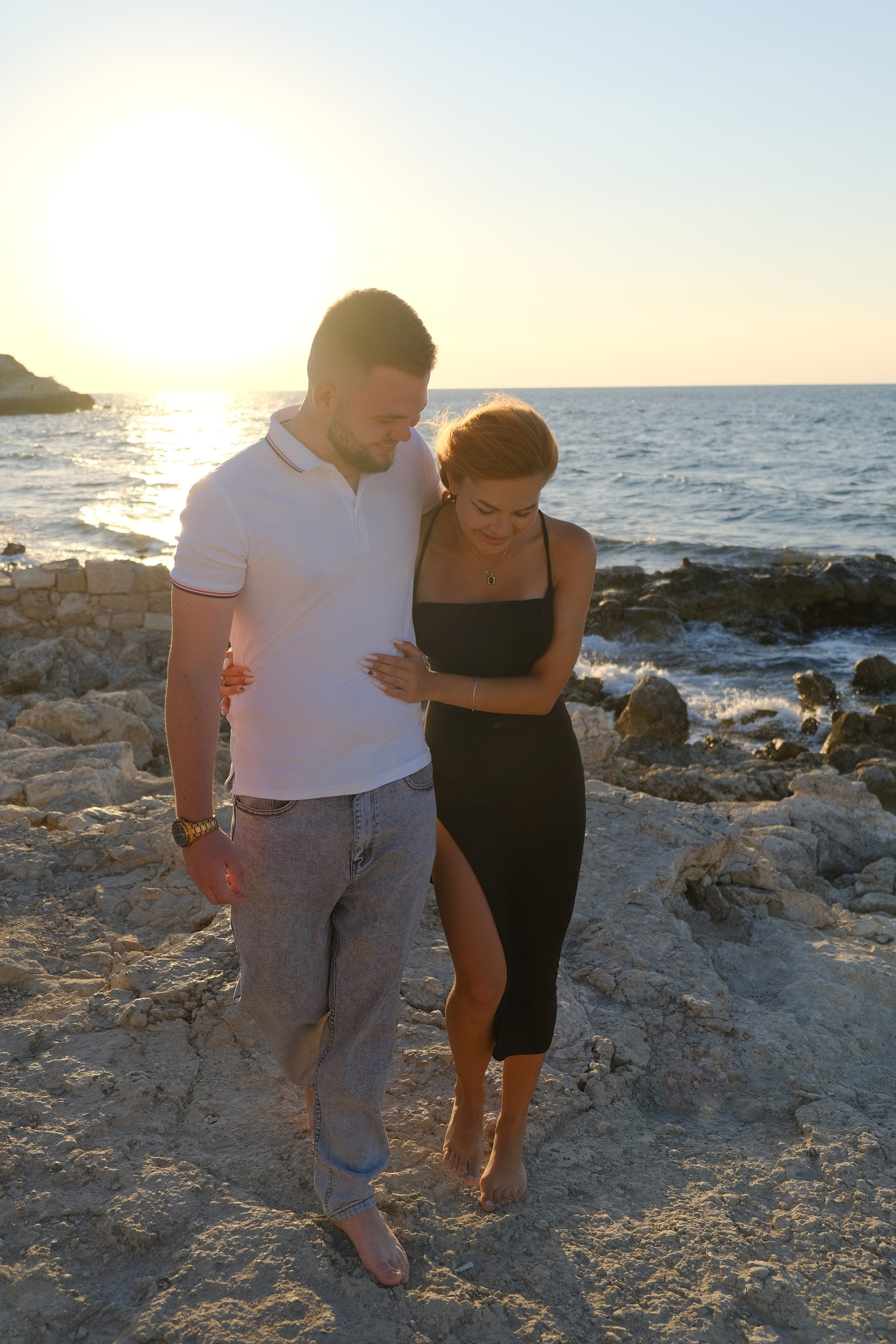 Молодая пара босиком стоит на пляже Херсонеса таврического у моря. Фотограф и видеограф Желдак Илья