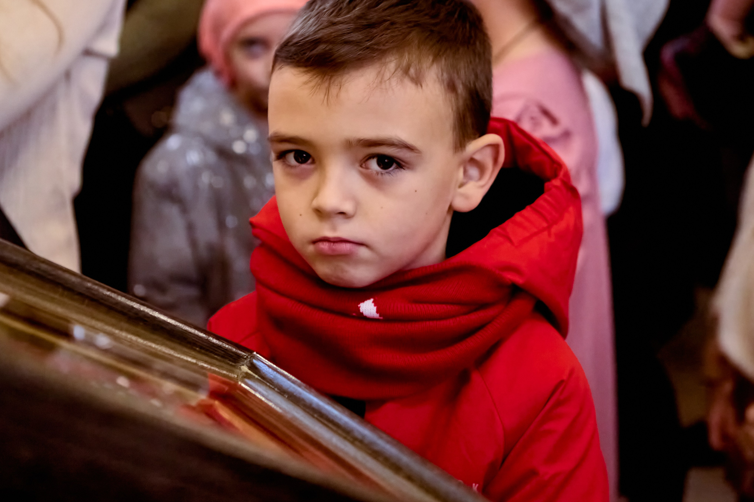 Мальчик в красной куртке стоит к причастию