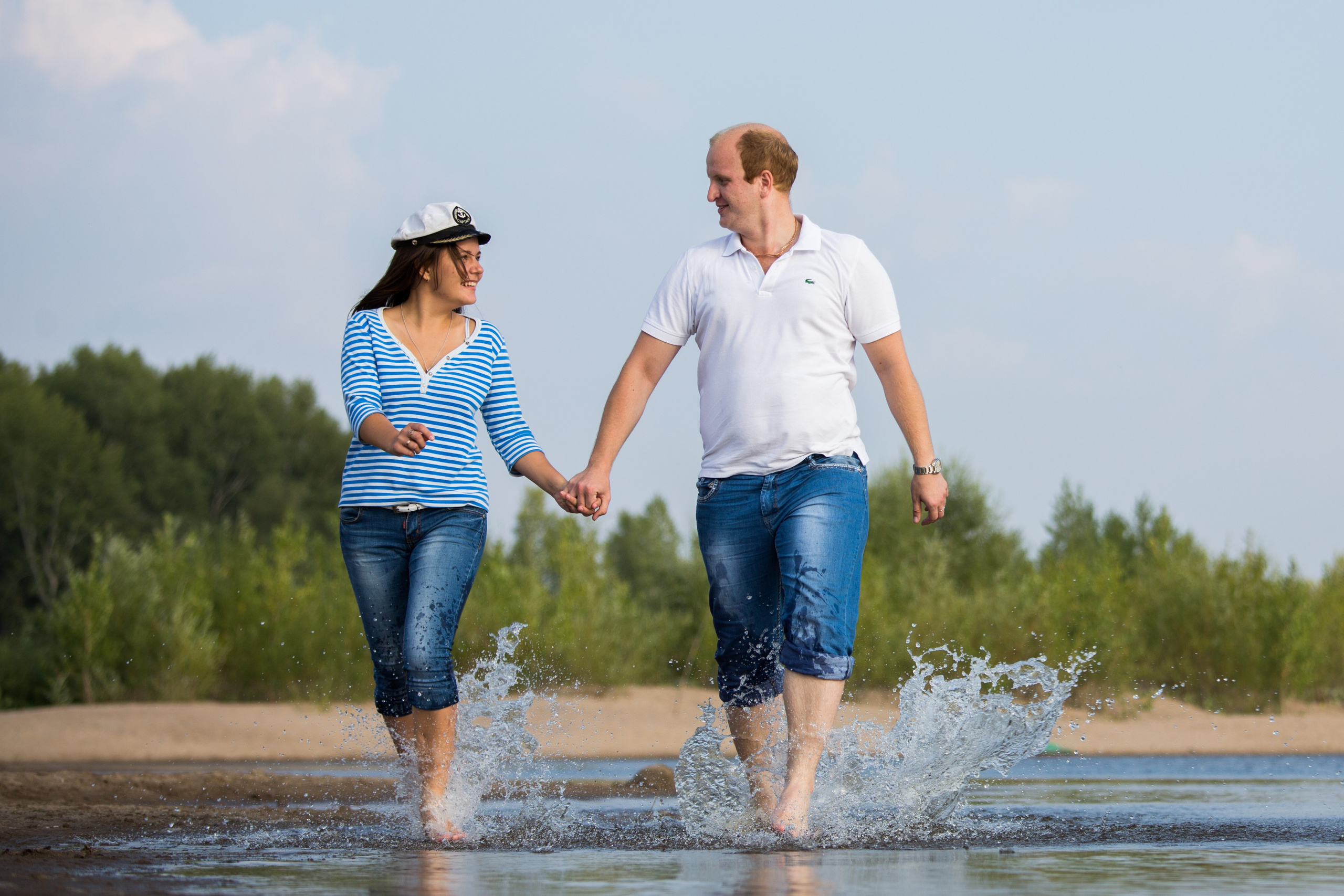 парень и девушка весело бегут по воде взявшись за руки 