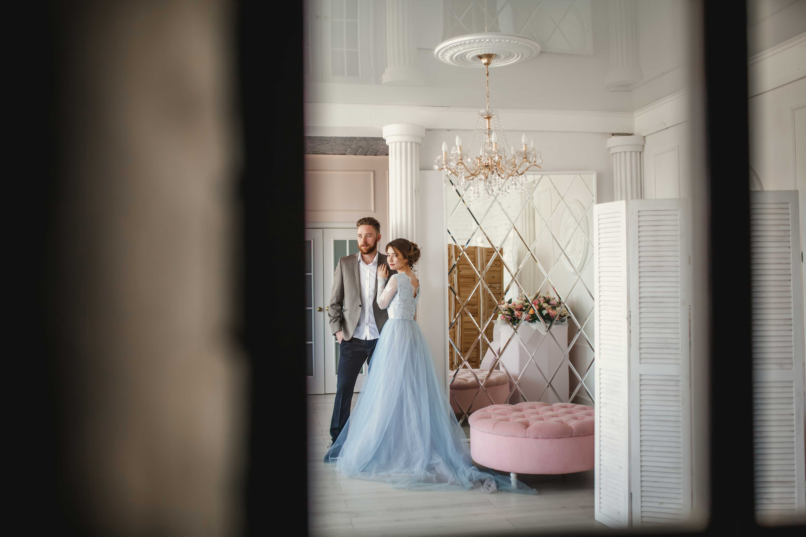 Нежная стильная невеста в голубом свадебном платье и высокий красивый жених с бородой стоят рядом