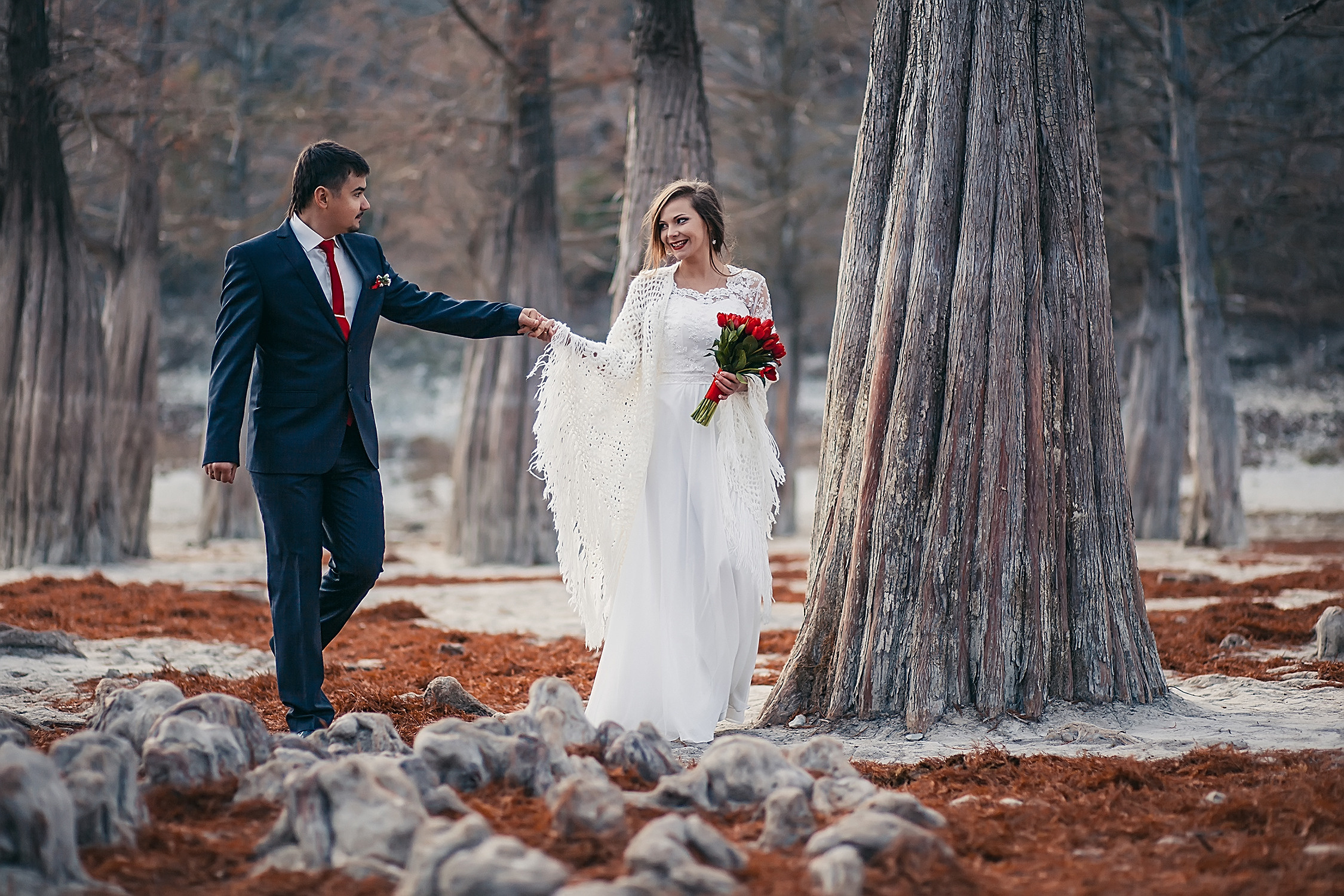 Жених и невеста идут взявшись за руки по осеннему лесу