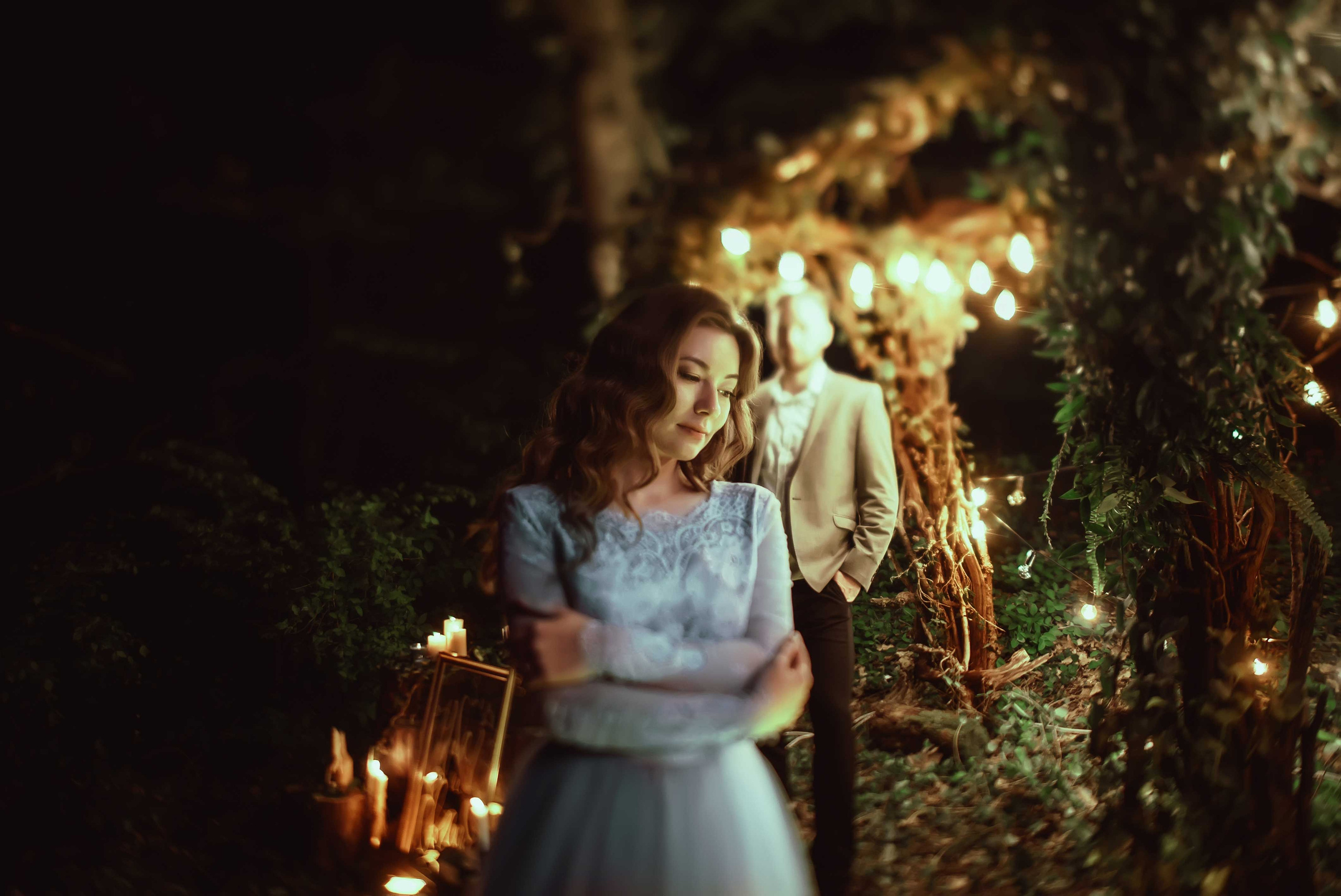 Невеста в голубом свадебном платье с каштановыми распущенными волосами ночью в лесу