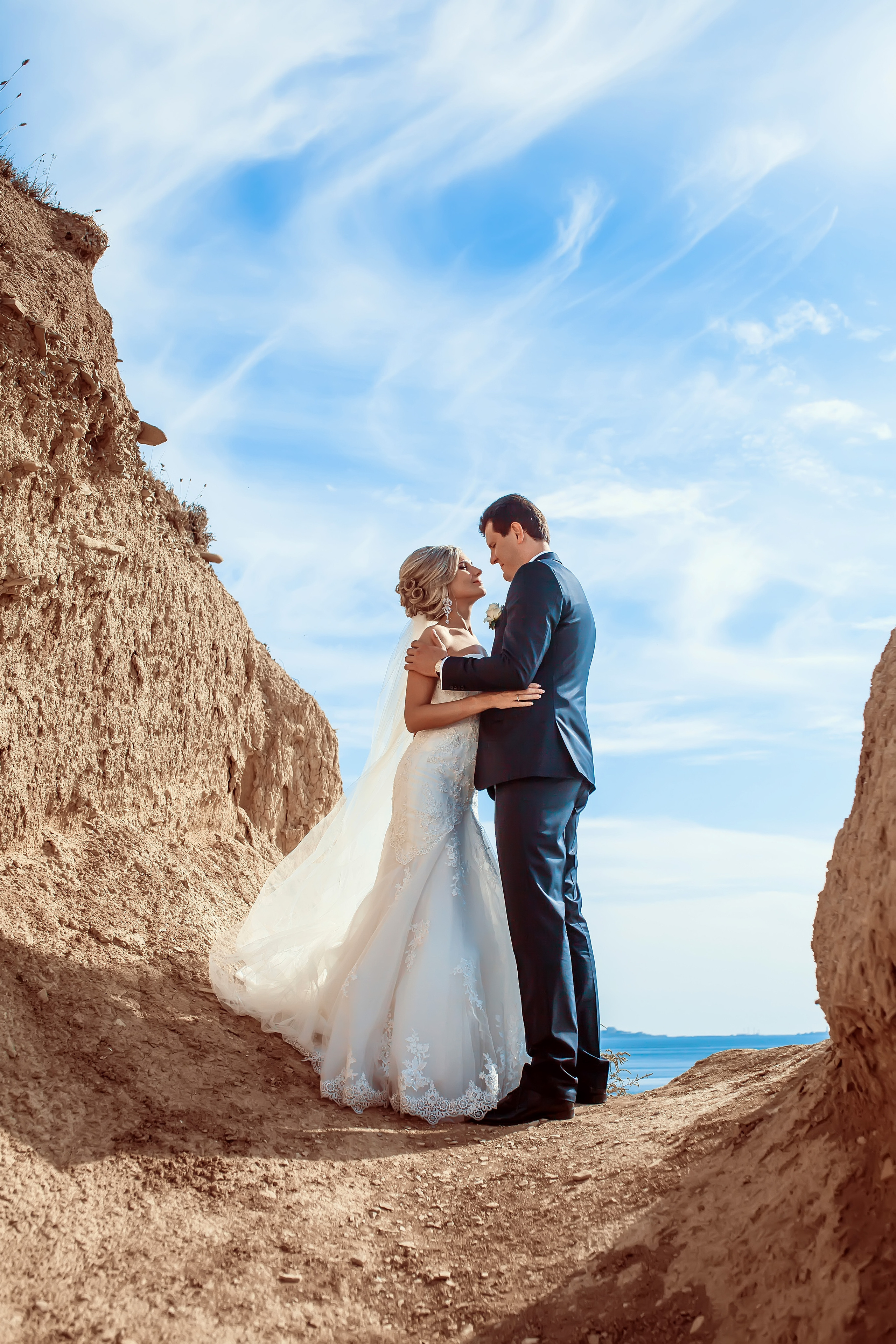 Жених и невеста стоят на фоне моря обнявшись