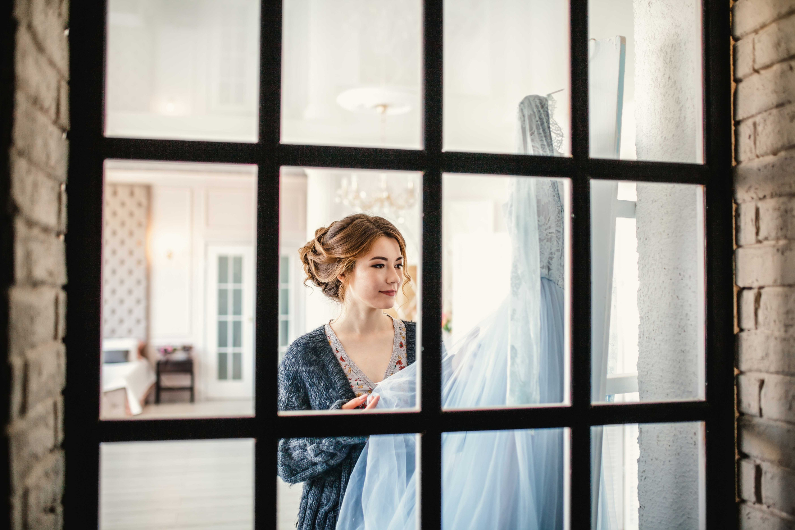 Красивая нежная невеста рассматривает свадебное платье