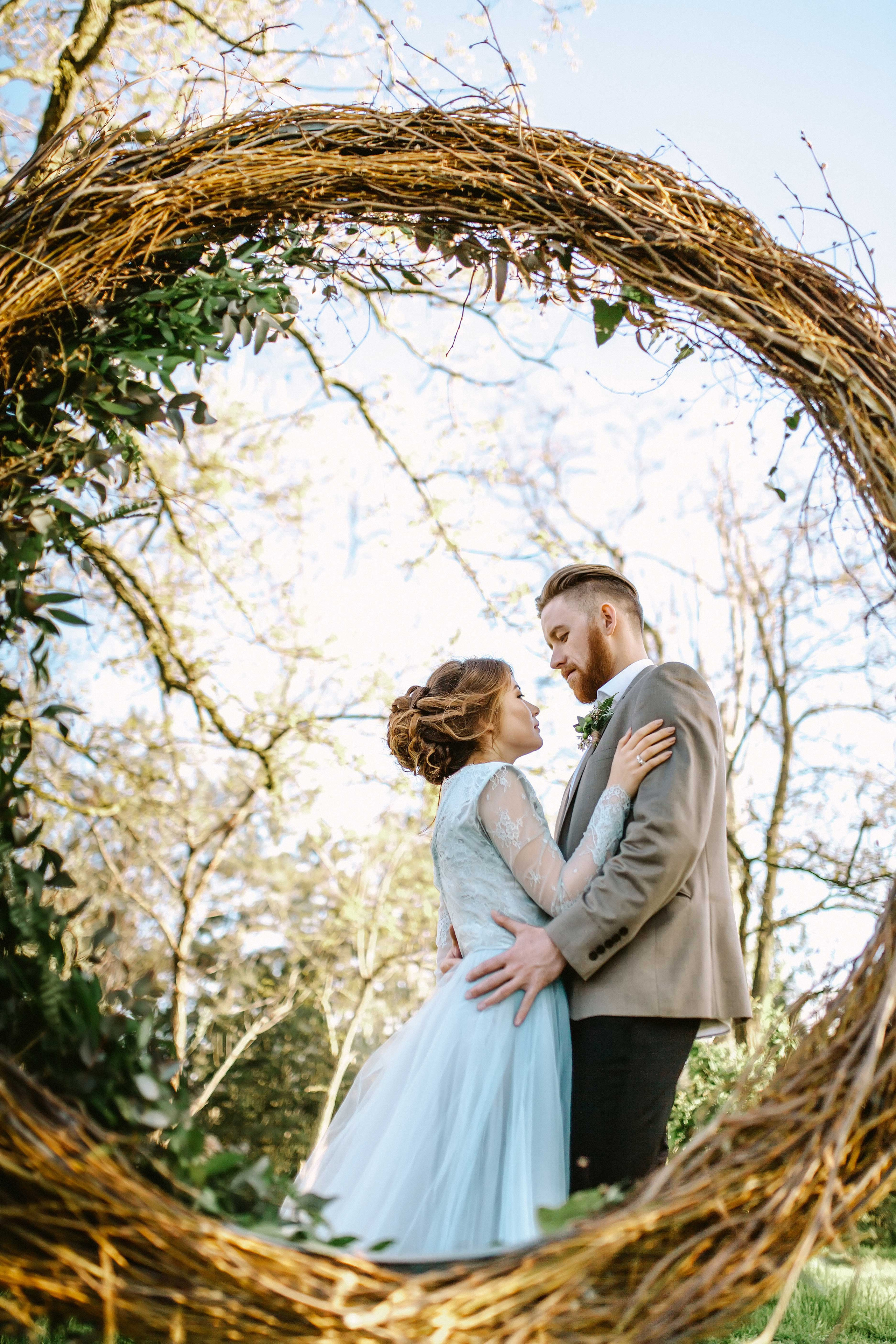 Нежная стильная невеста в голубом свадебном платье и высокий красивый жених с бородой стоят обнявшись