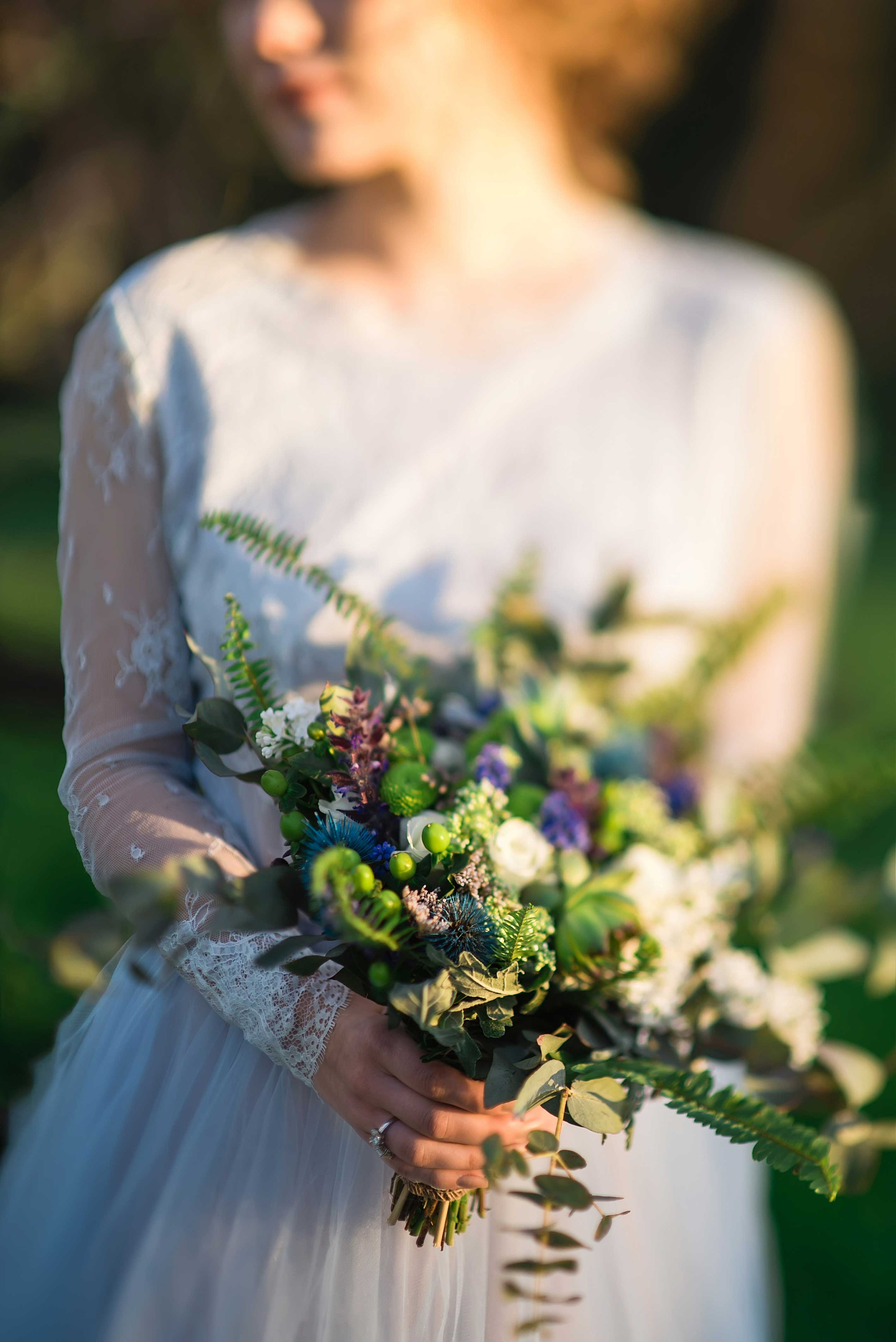 Невеста в голубом свадебном платье держит в руках растрепанный свадебный букет