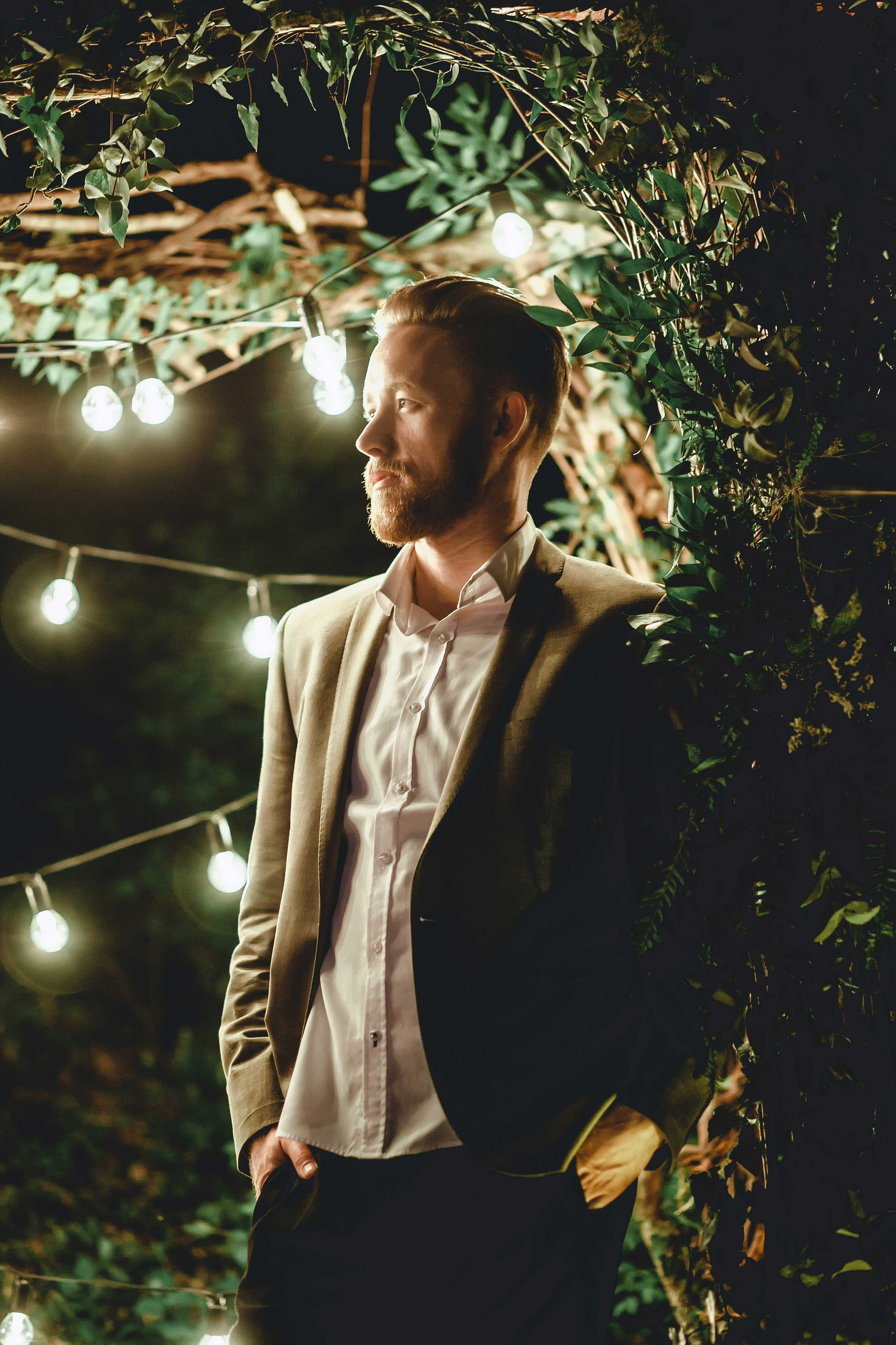 Жених стоит ночью в лесу украшенном гирляндами