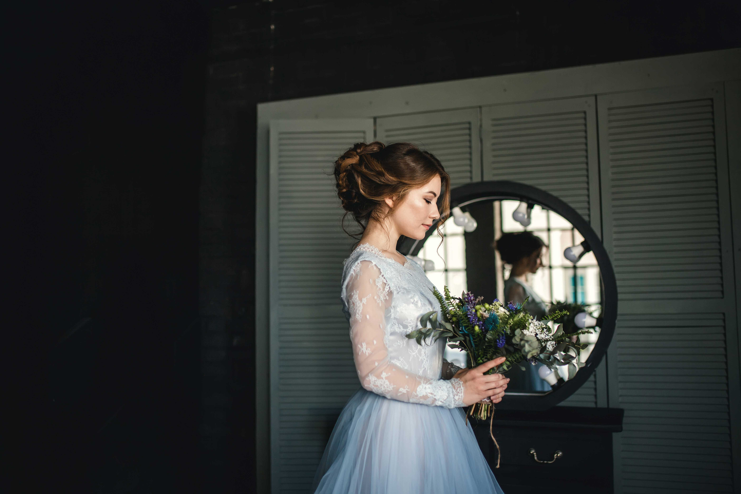 Нежная стильная невеста в голубом свадебном платье держит в руках растрепанный свадебный букет