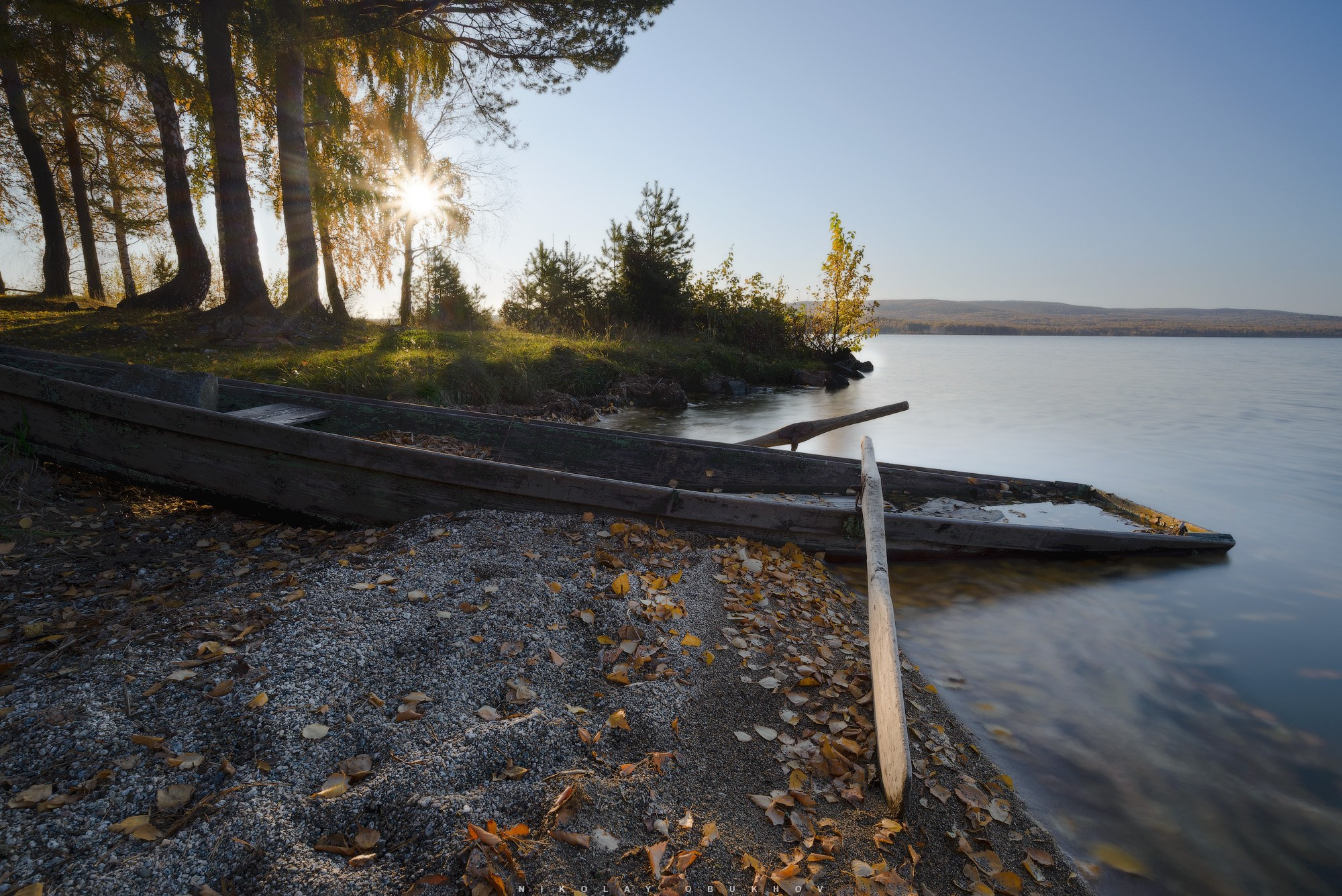 Старая лодка в осеннее морозное утро на берегу озера.