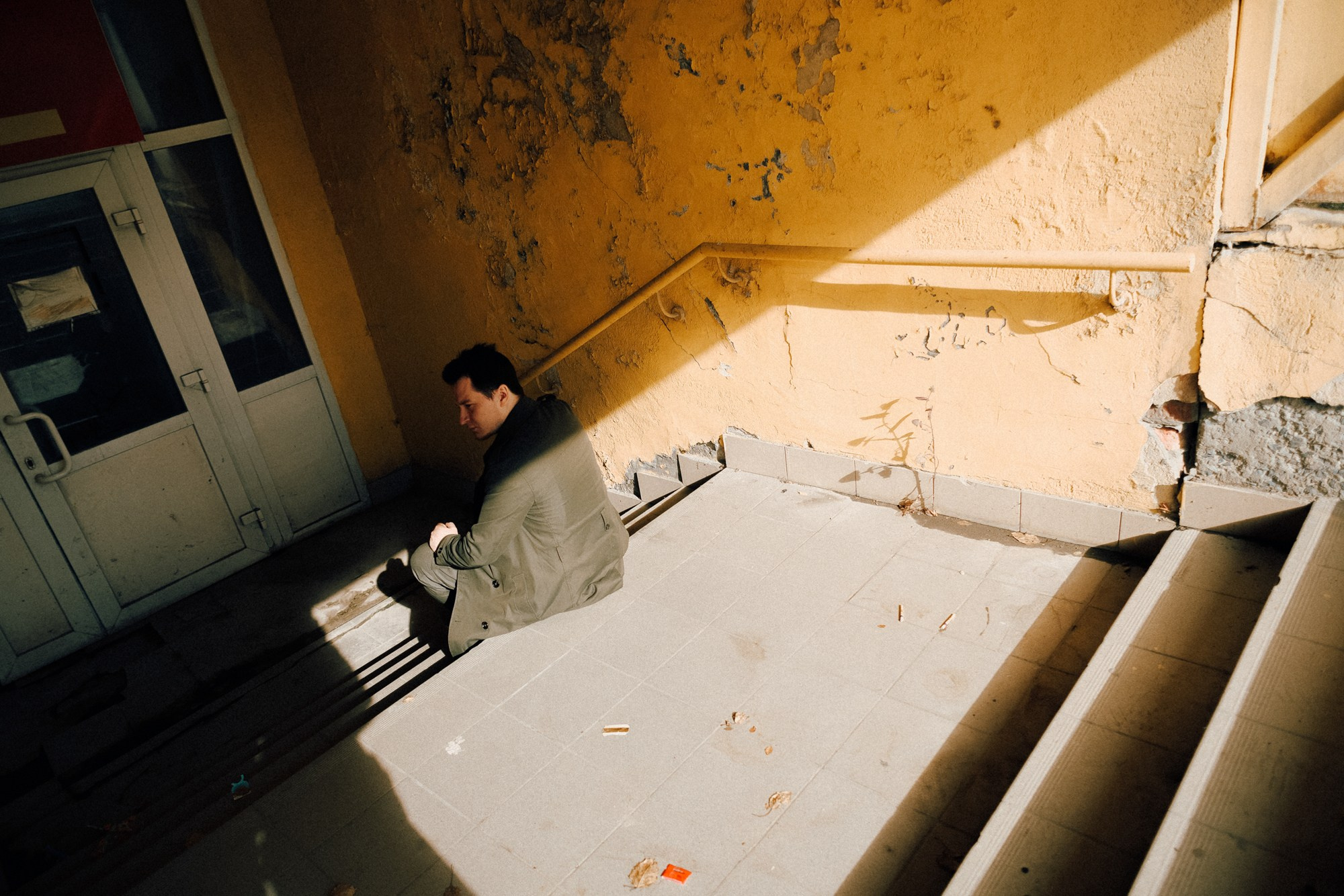 Парень сидит на ступенях в тени, эстетика одиночества и переезда