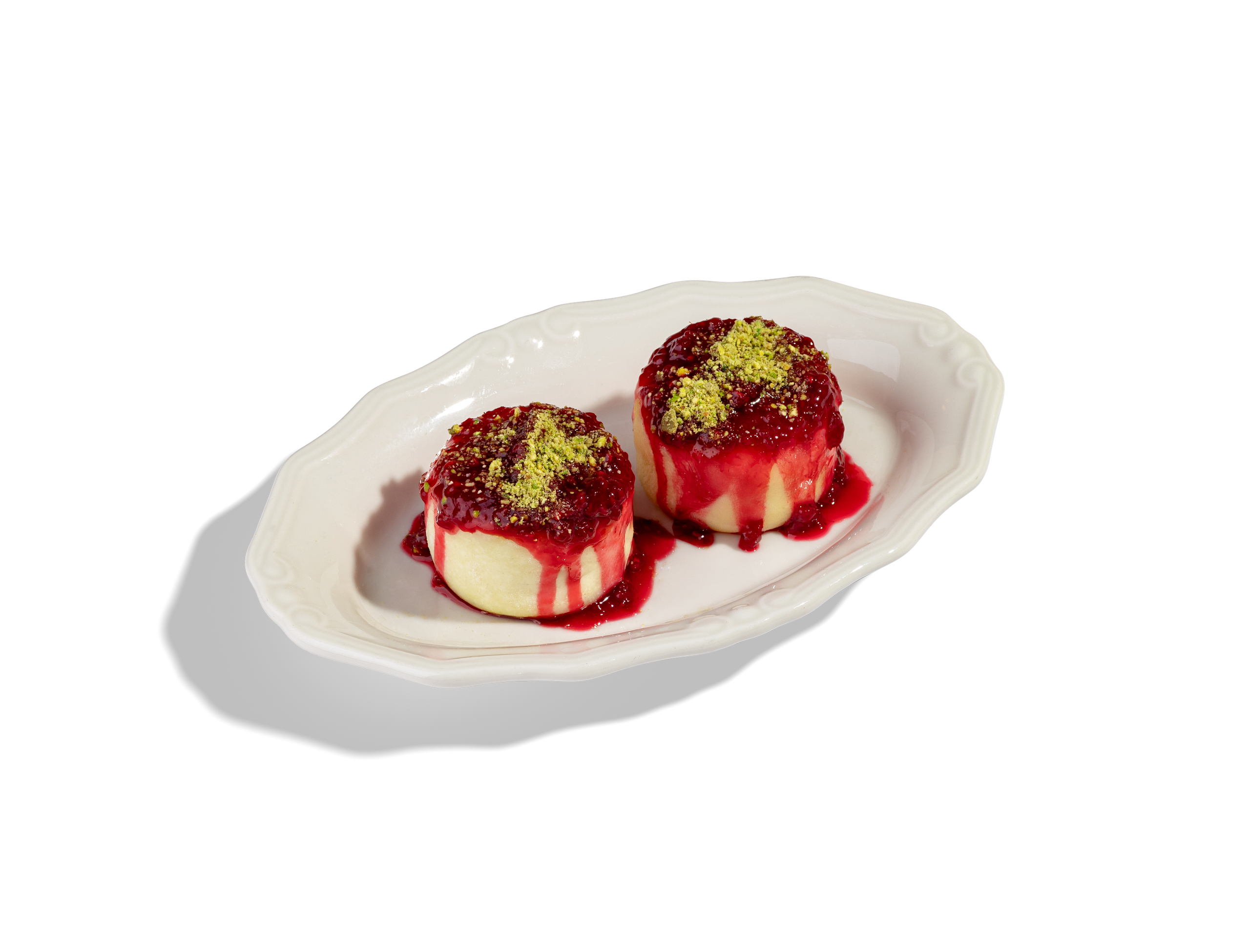 Сырники с малиной и фисташкой  — 590₽. Сырники из фермерского творога (2шт) с соусом из малины и свежей фисташки 