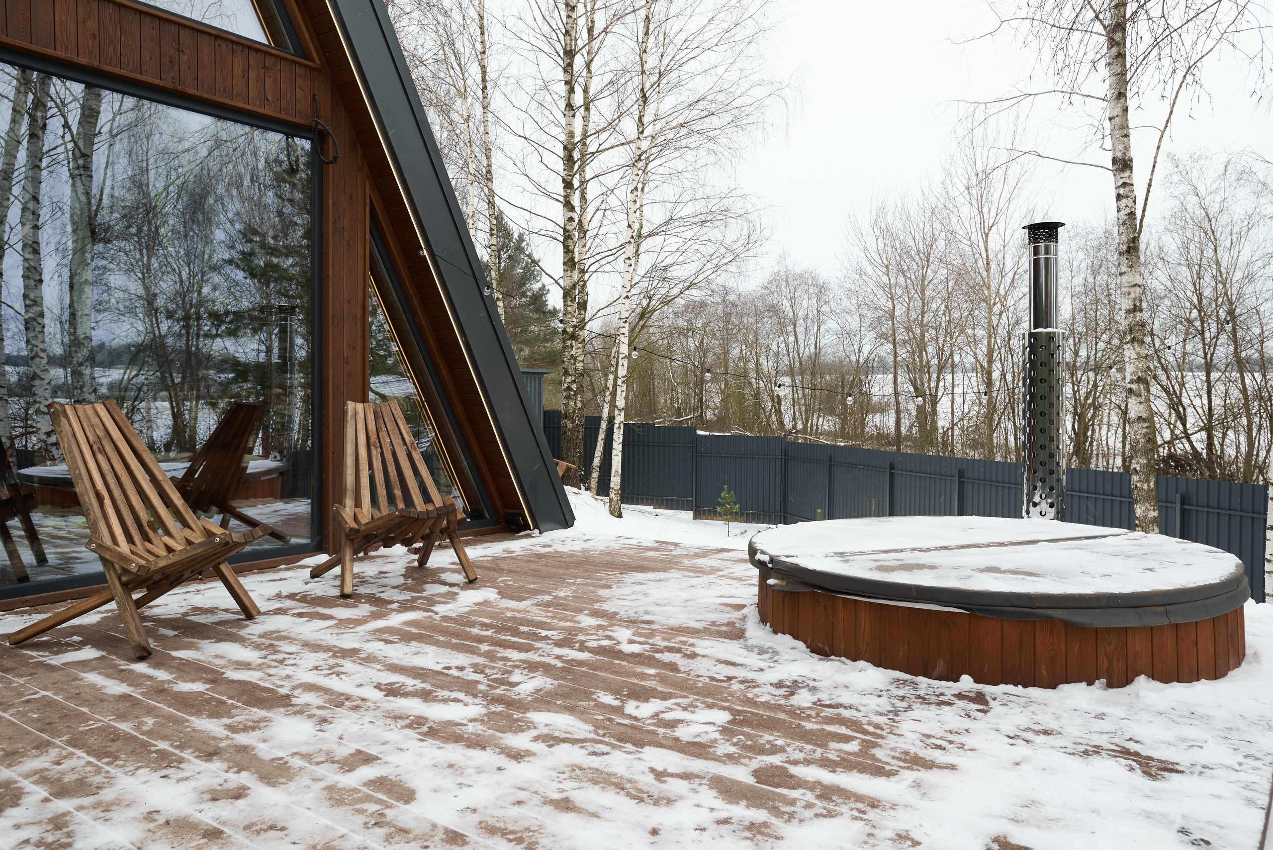 Съёмка зоны отдыха у дома с купелью, креслами и видом на фасад A-frame