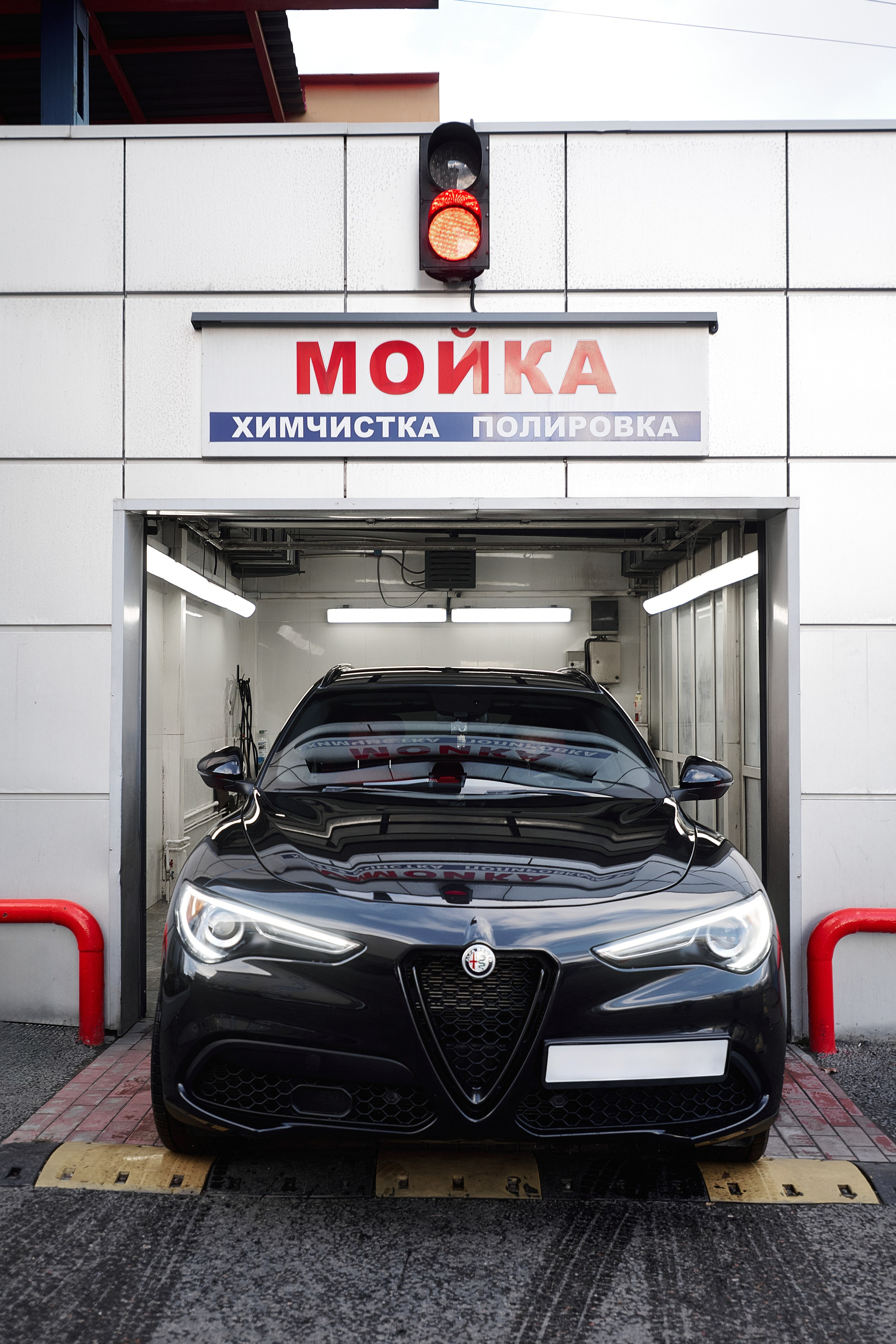 Фотосъёмка чёрного Alfa Romeo Stelvio у входа в автомойку
