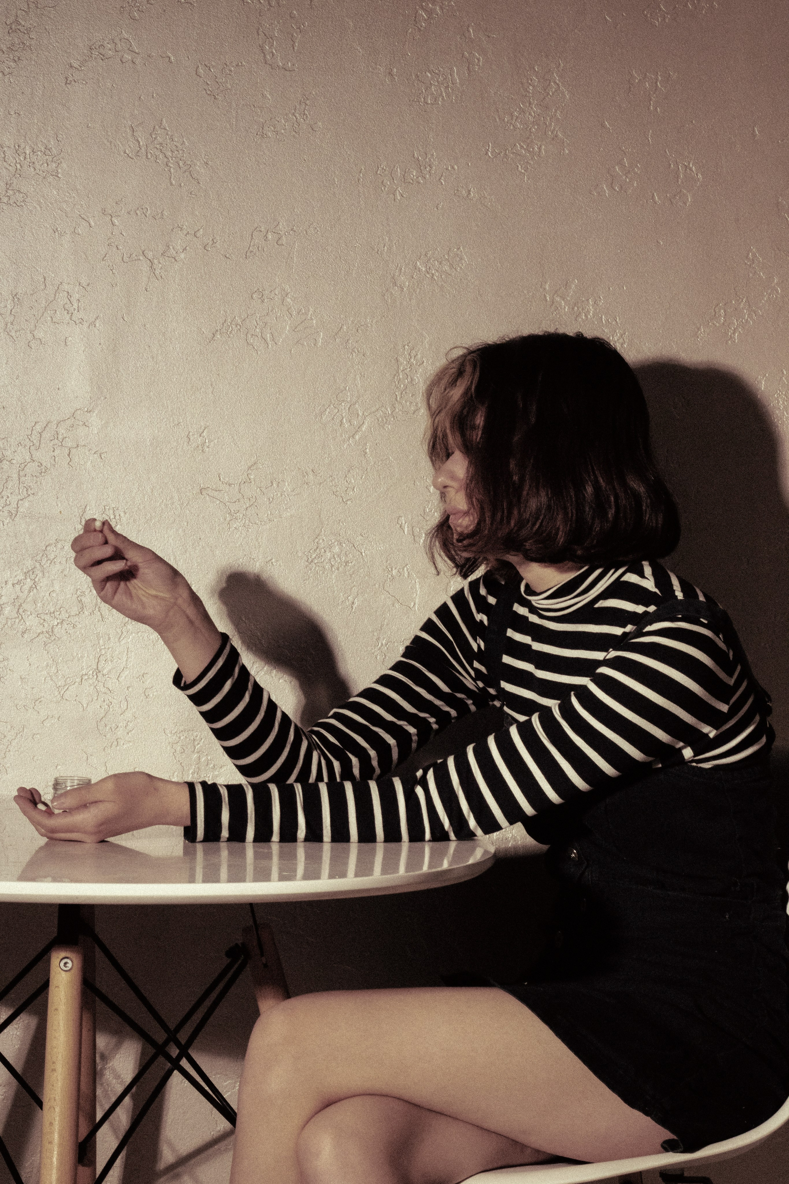 Девушка разглядывает таблетку в руках, опустив голову — в поисках ответов в мелочах прошлого.