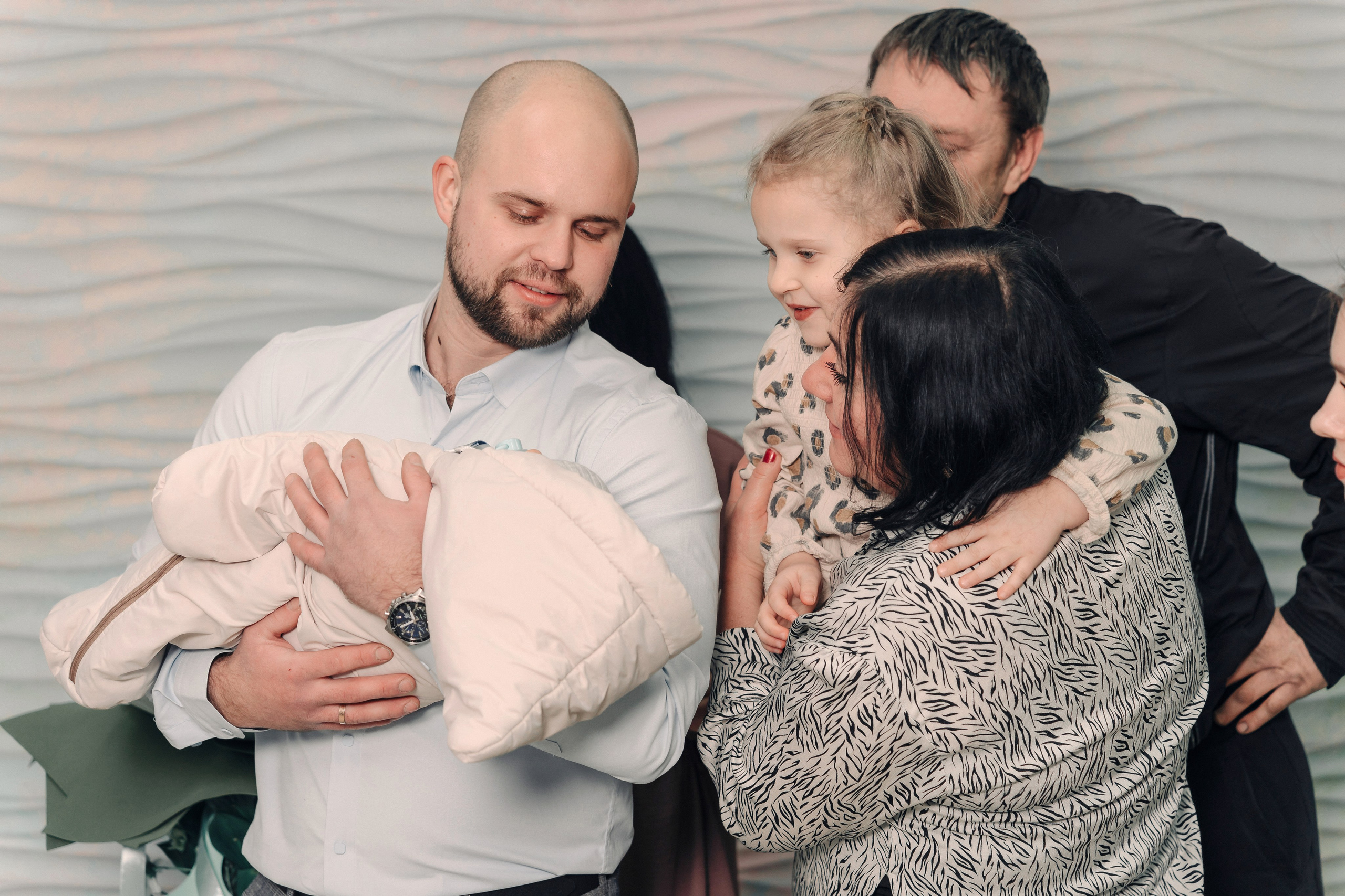 Отец держит новорожденного на руках.