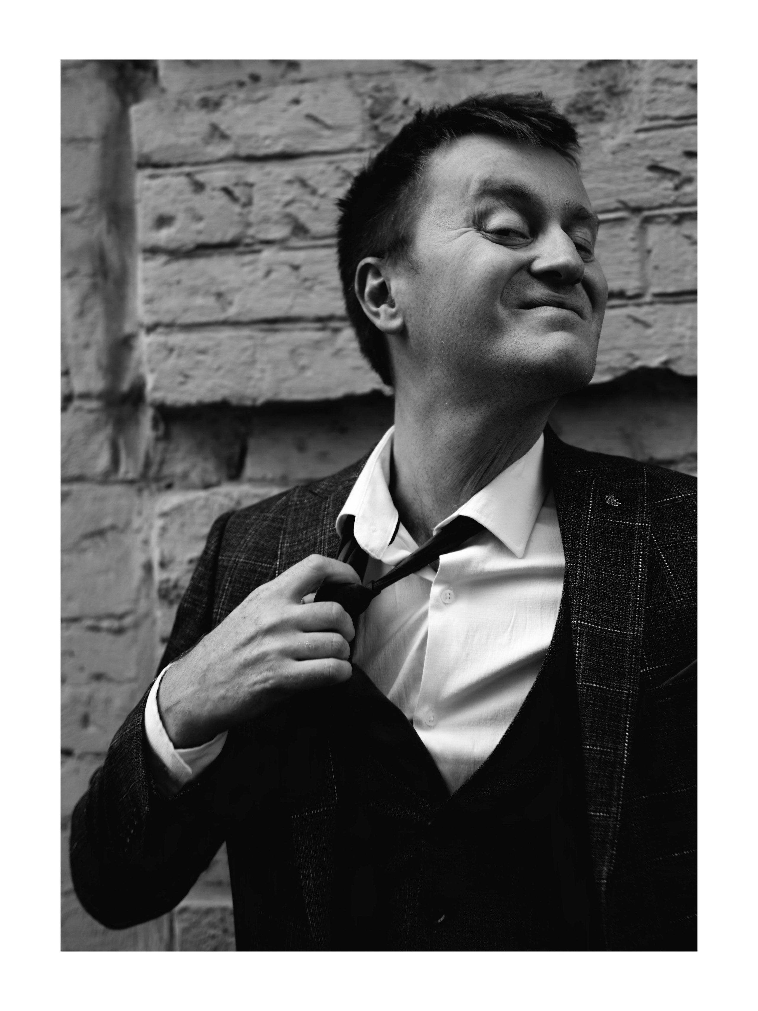 мужчина тянет себя за галстук