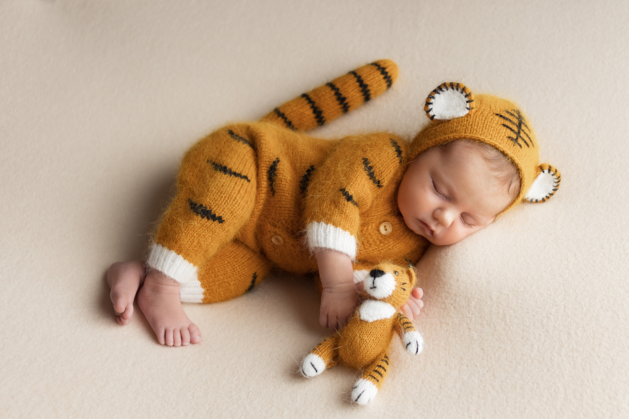 Младенец позирует на боку в костюме трикотажном Тигр