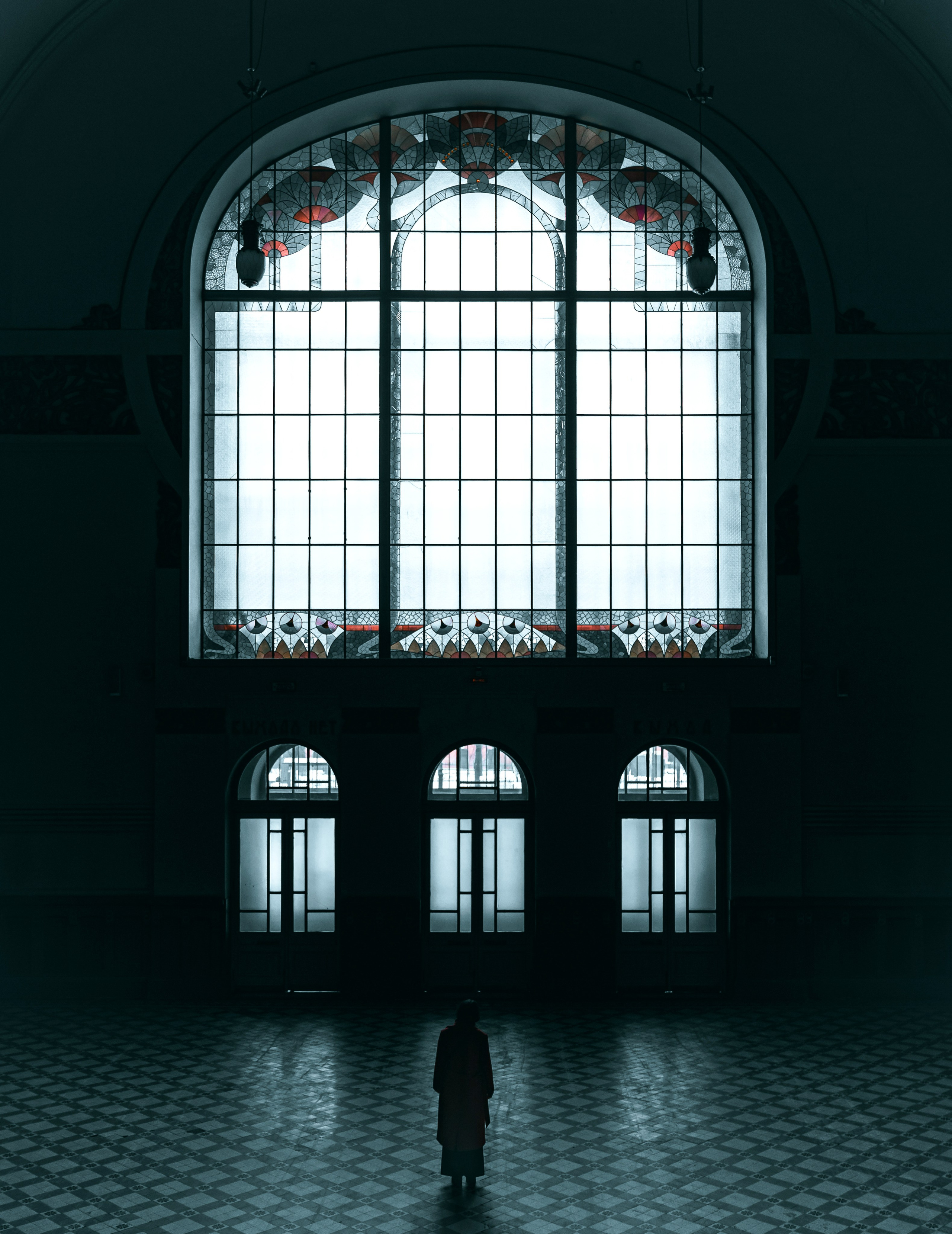  Витебский вокзал. Одинокая женщина в пальто стоит в огромном пустом зале с витражами Санкт-Петербурга, чёрно-белый интерьерный кадр, urban меланхолия Ev.Rednix.