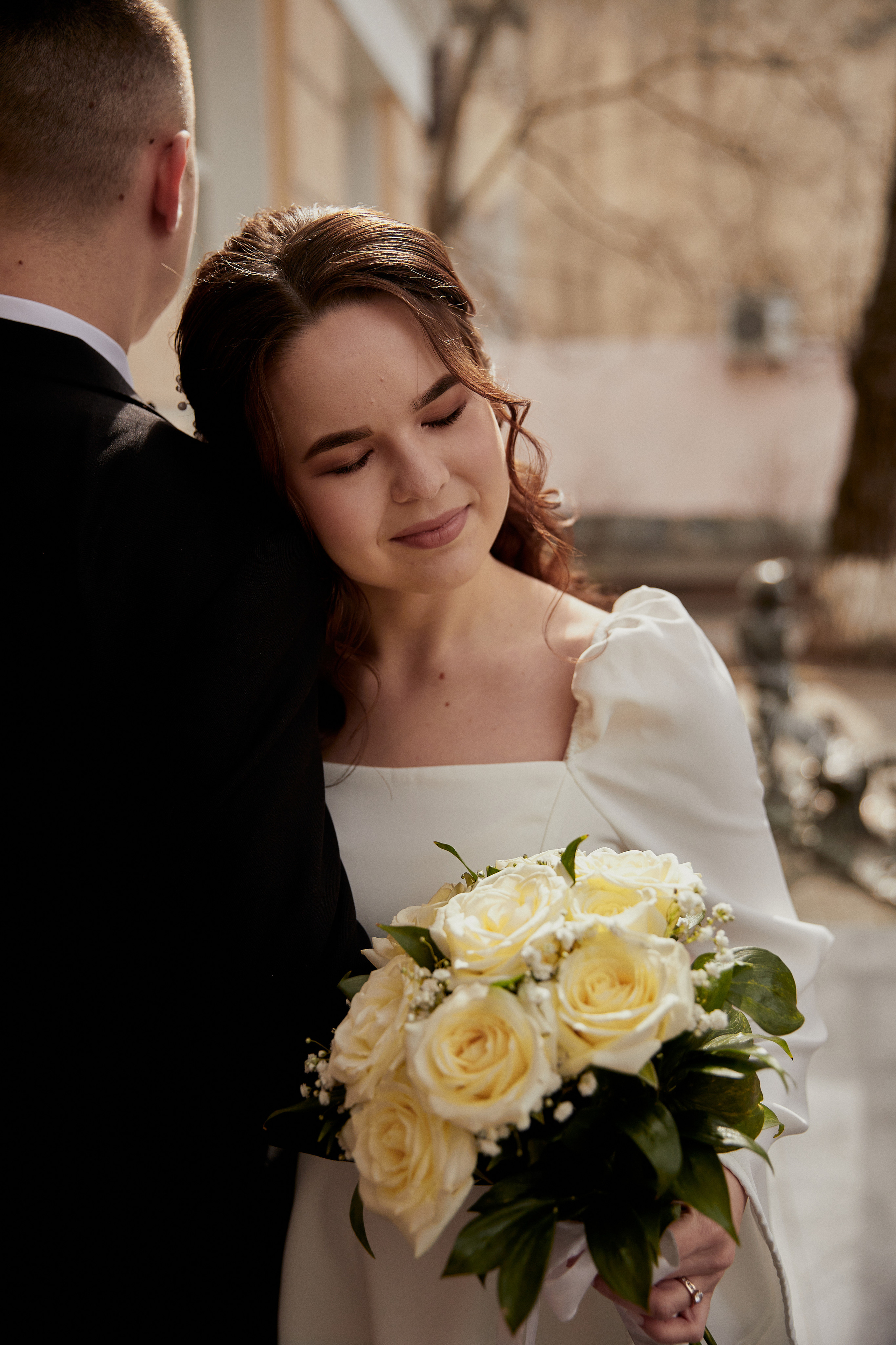 Невеста  с букетом цветов облокотилась на плече жениха