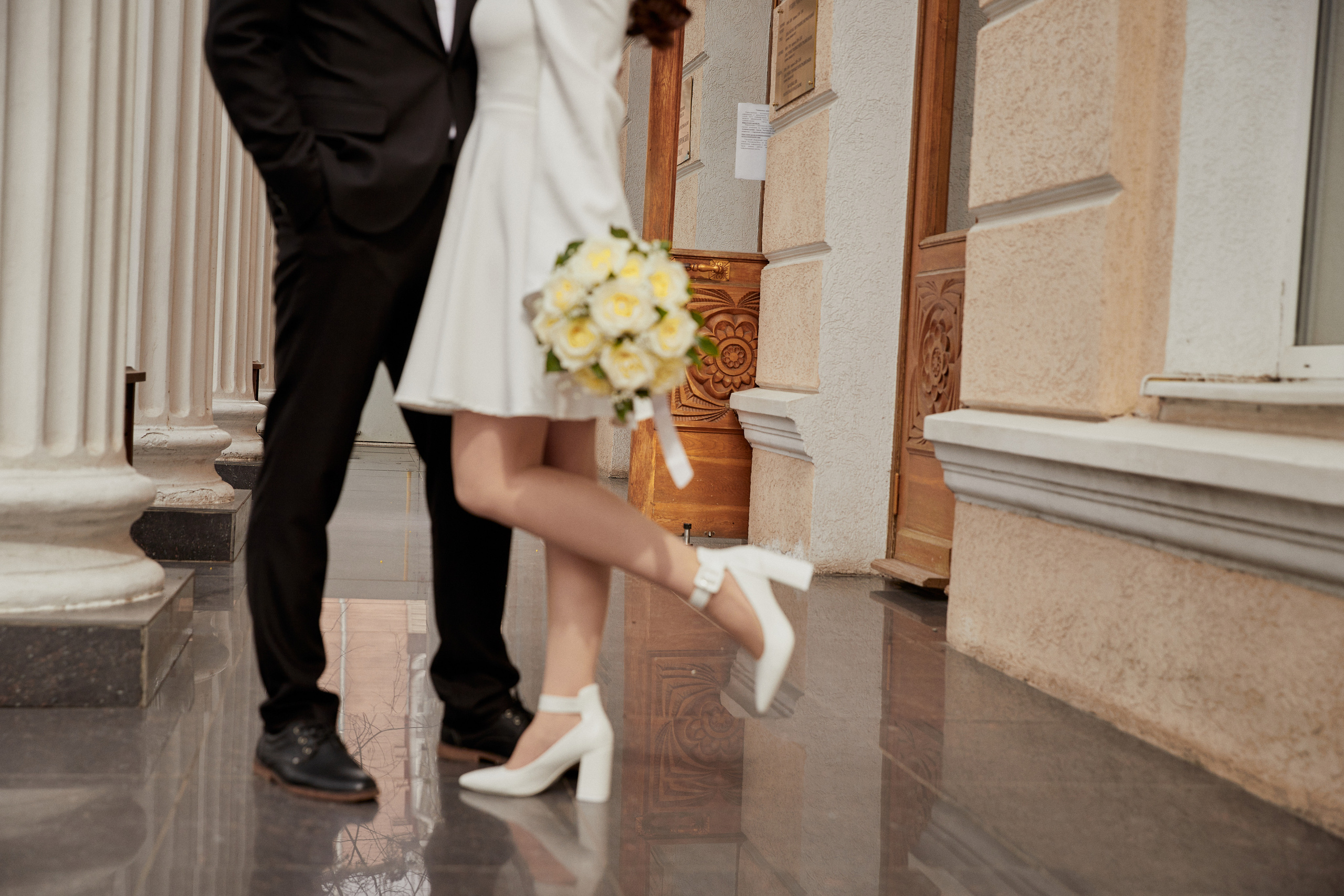 Жених и невеста с букетом цветов на пороге загса.