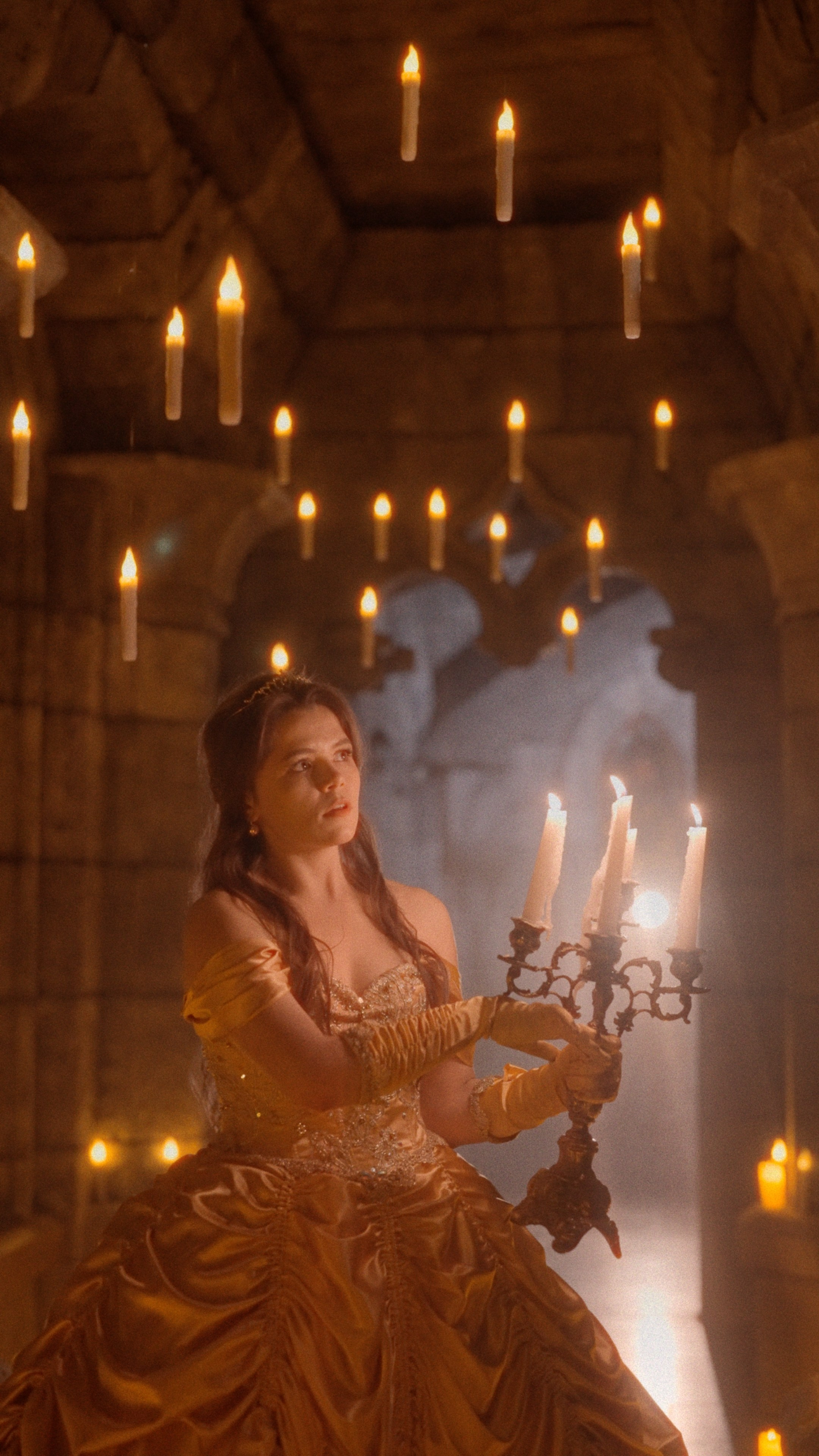 Девушка в роскошном золотом платье держит канделябр, окружённая мерцающими свечами в таинственном коридоре замка Гарибальди.