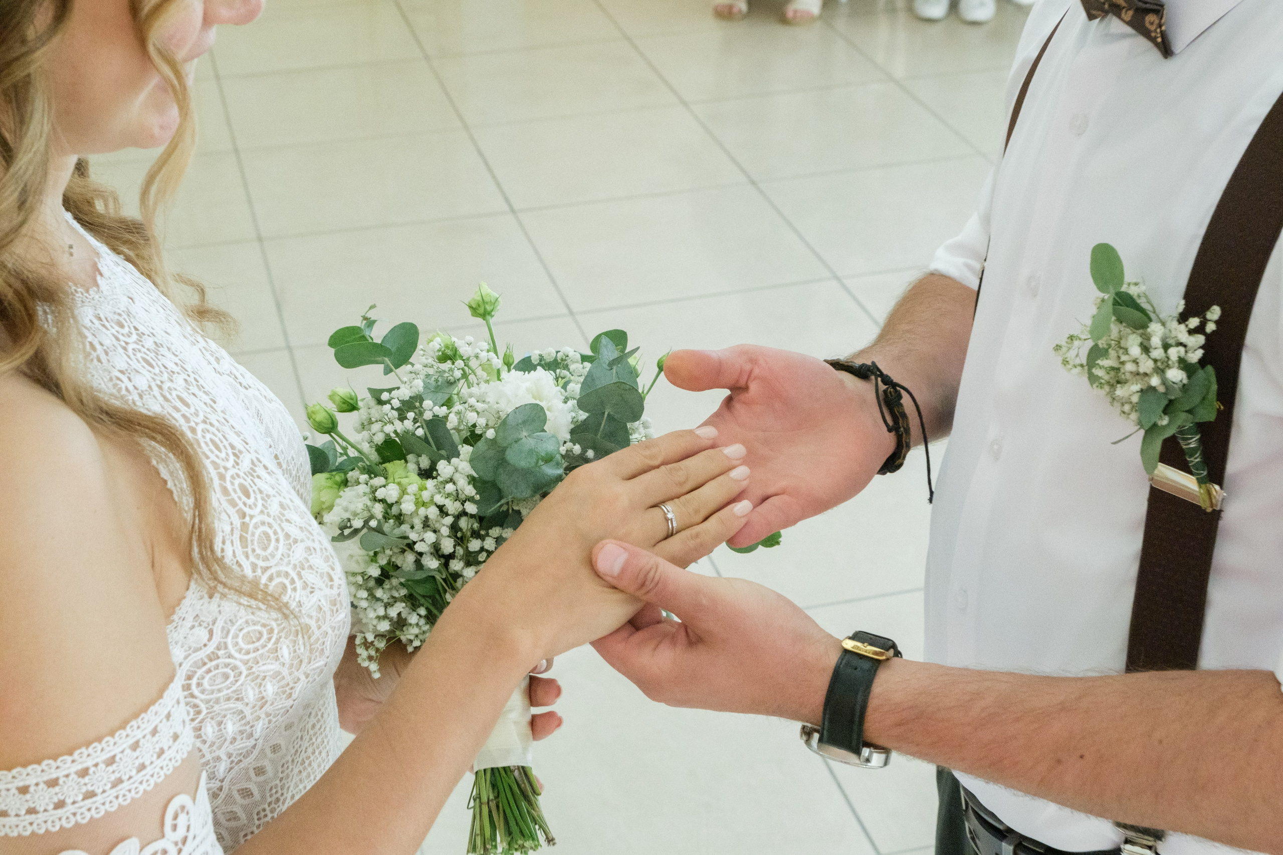 Момент обмена кольцами: крупный план рук молодоженов во время церемонии, когда они надевают друг другу обручальные кольца