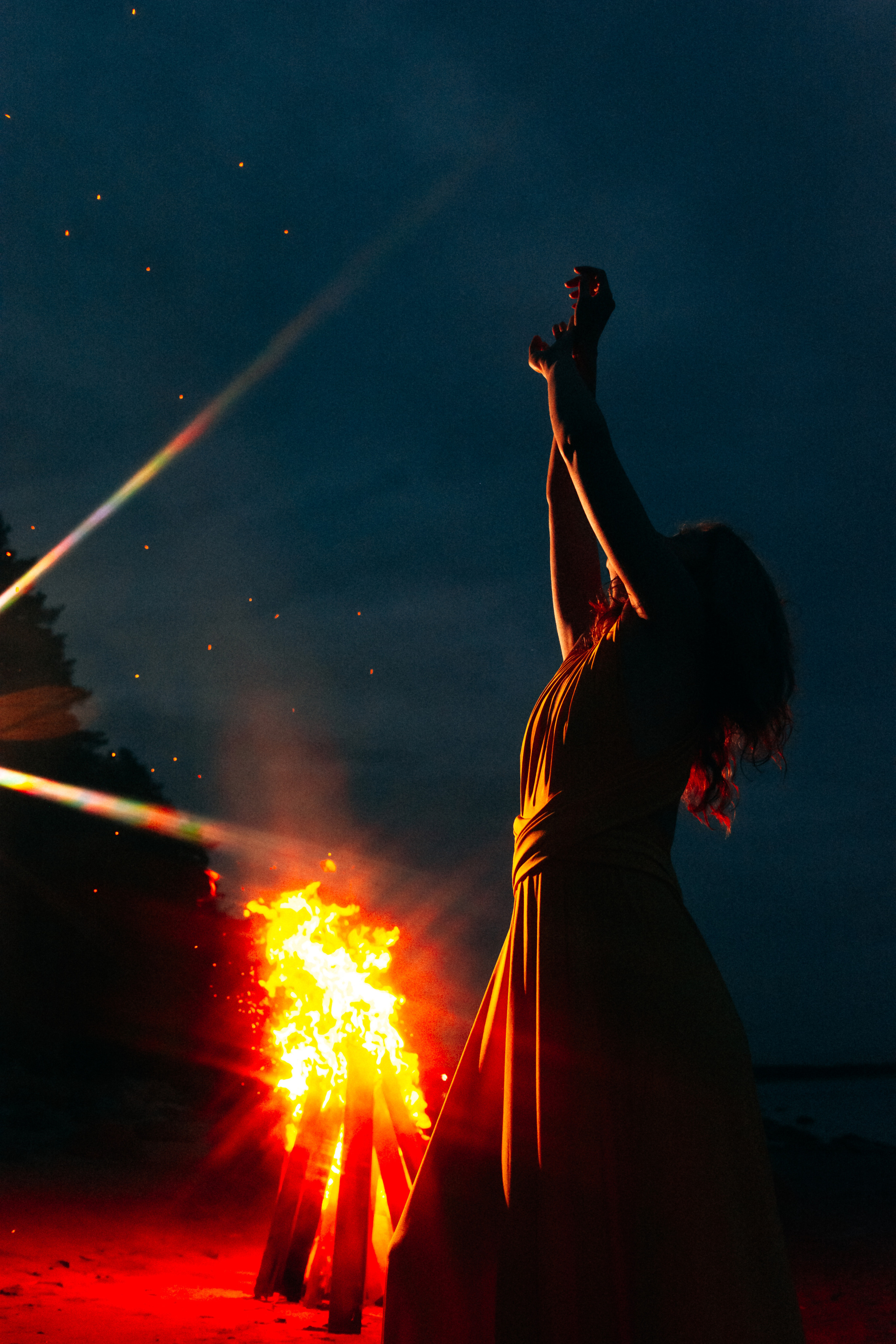  Огонь на песчаном пляже Финского залива создаёт магическую атмосферу, а девушка в желтом платье придает композиции яркий акцент и энергию.