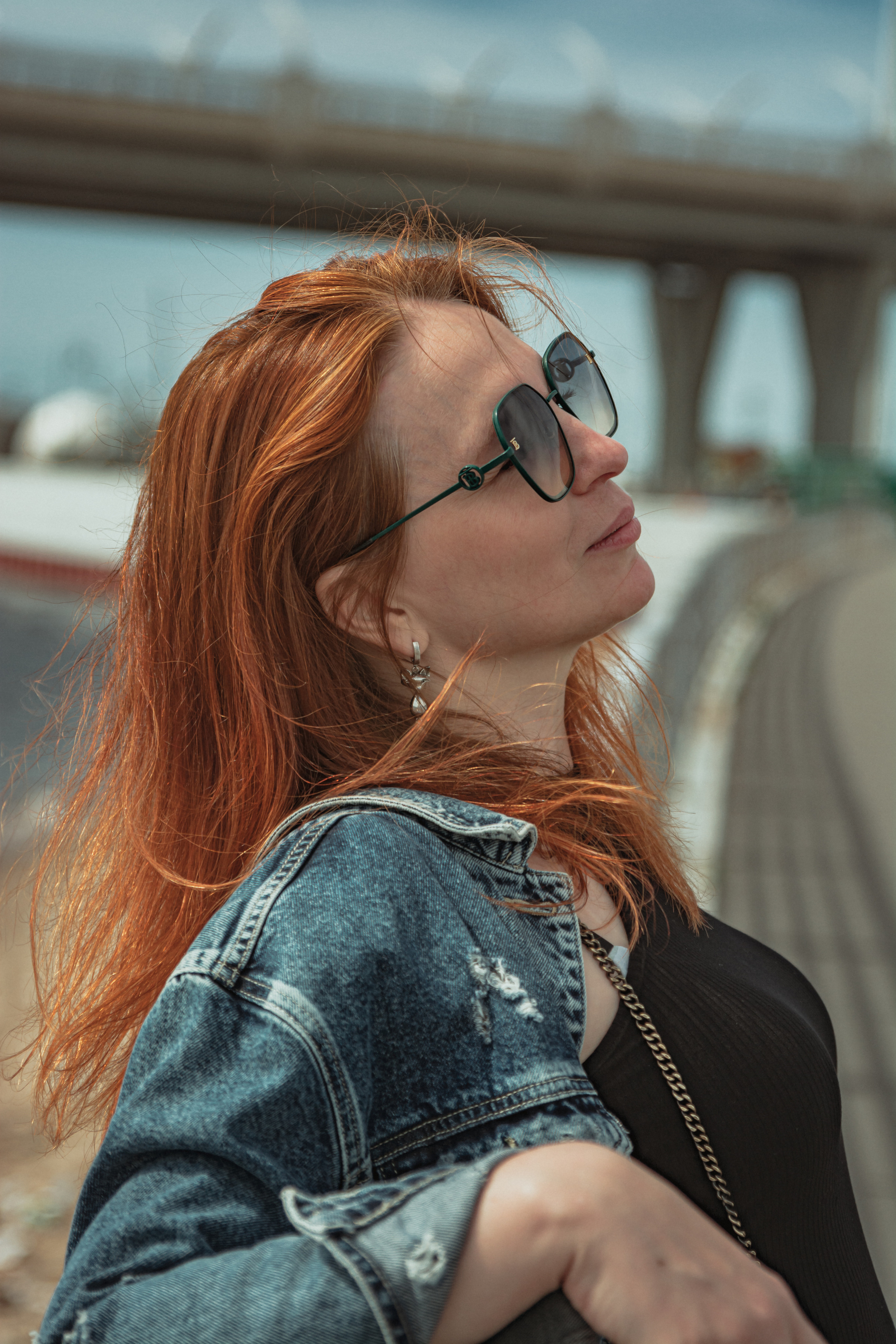 Рыжеволосая девушка у моста на набережной кайфует