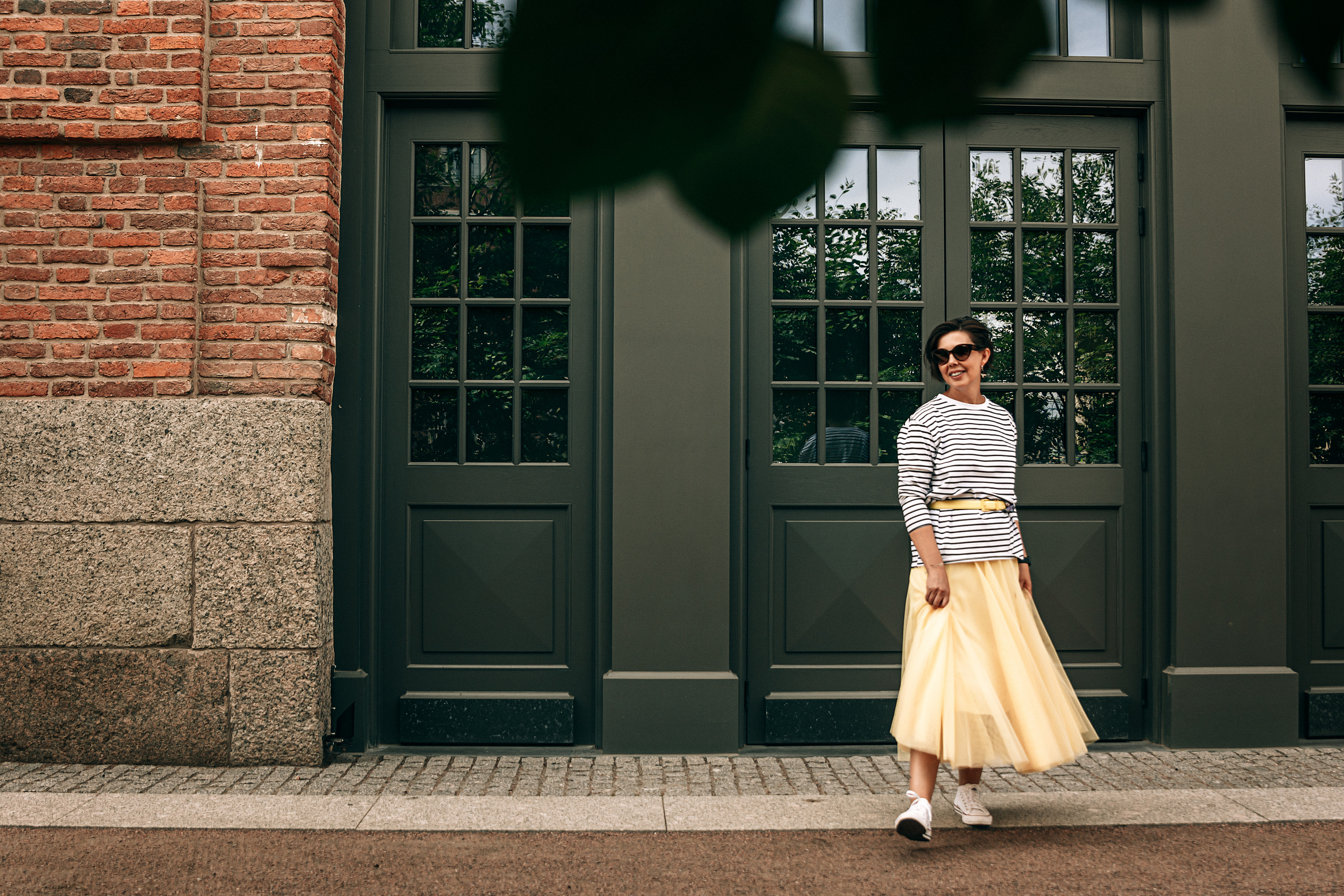 Легкая и модная фотосессия с девушкой в яркой жёлтой юбке и тельняшке, проходящая по знаковым местам Петербурга, включая Новую Голландию.