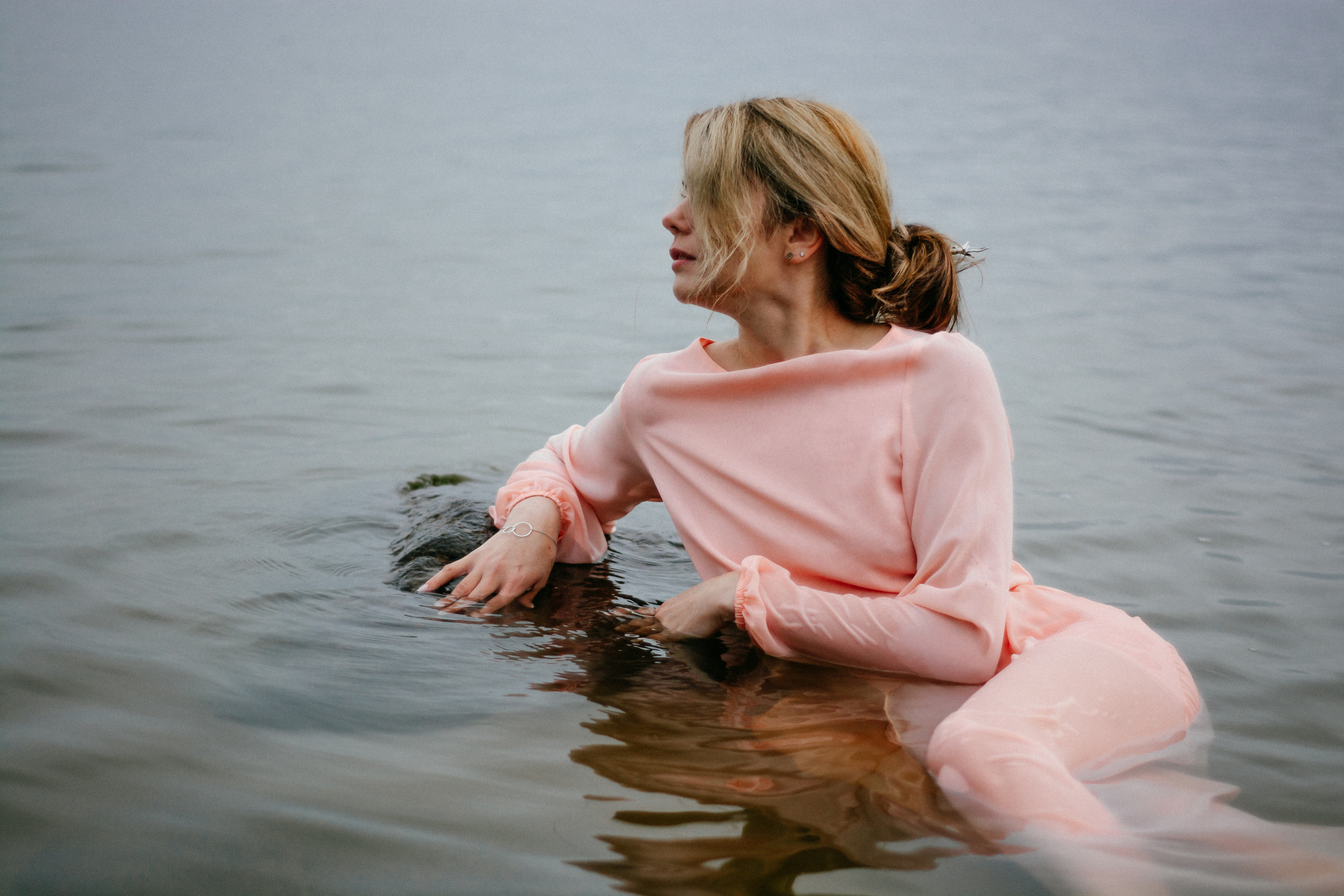  Розовое платье девушки создает контраст с окружающей синевой, добавляя чувственности и изящества в этой водной композиции.