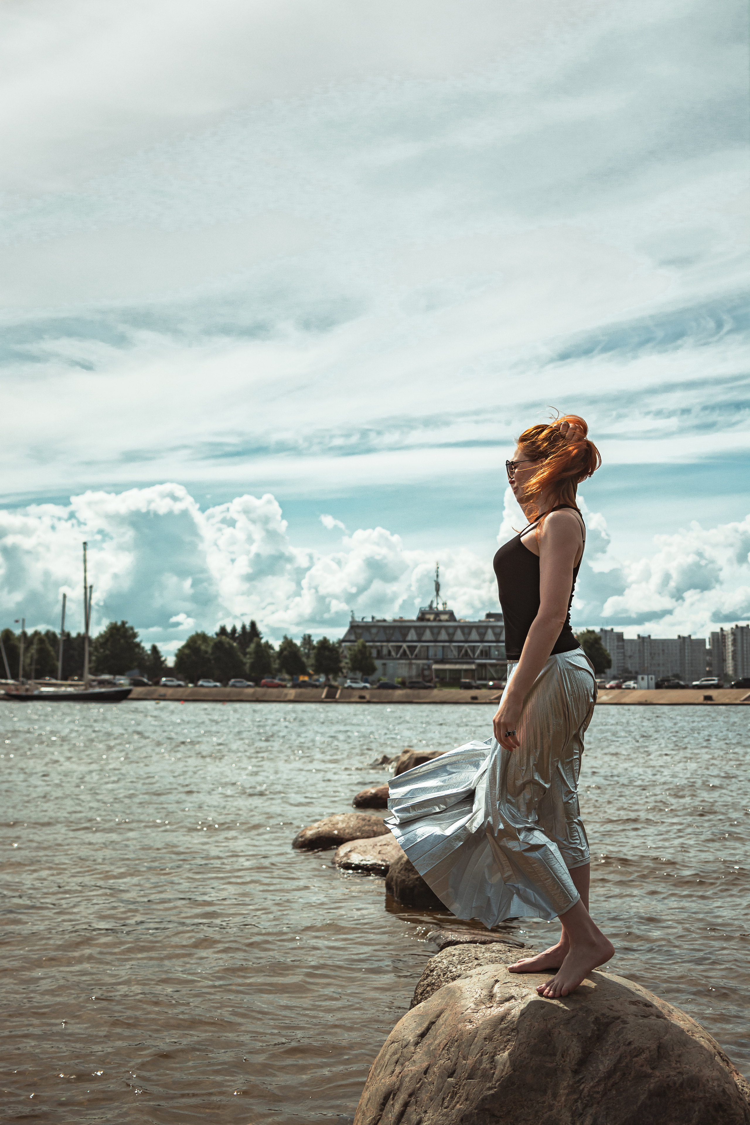 Рыжеволосая девушка стоит на камнях