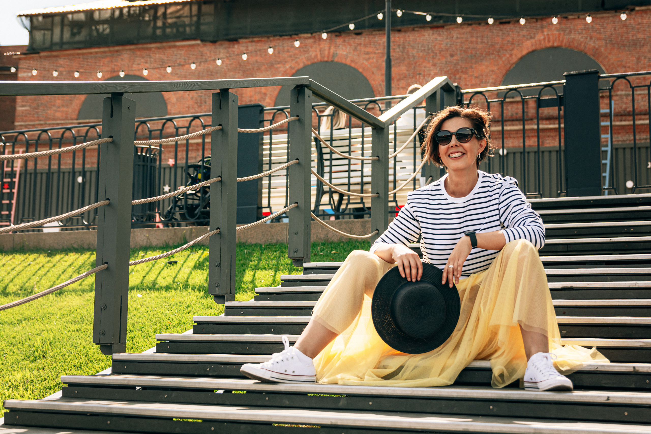 Привлекательная девушка в ярком образе жёлтой юбки и тельняшки позирует на фоне Петербурга, Новая Голландия.