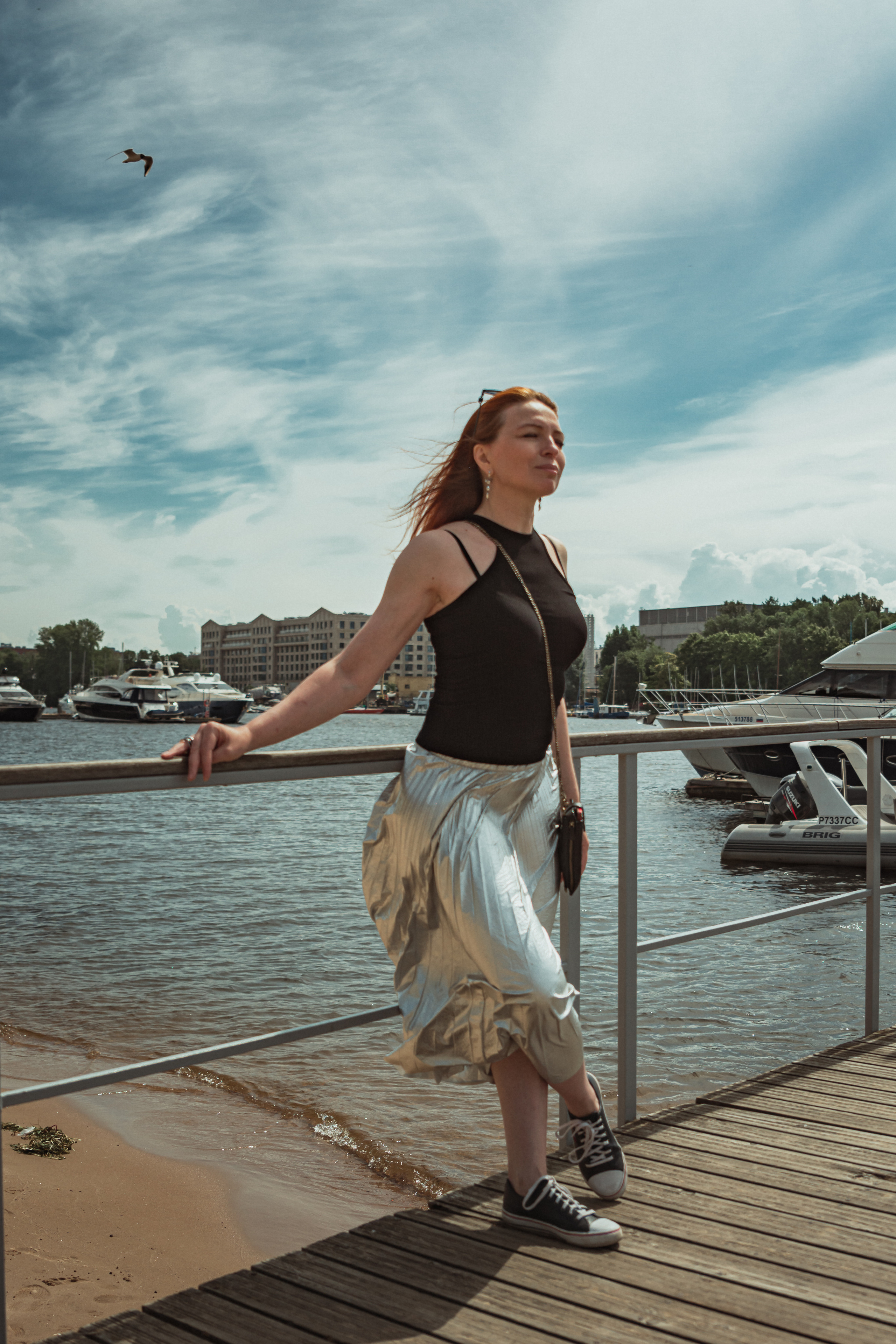 Рыжеволосая девушка стоит на пирсе