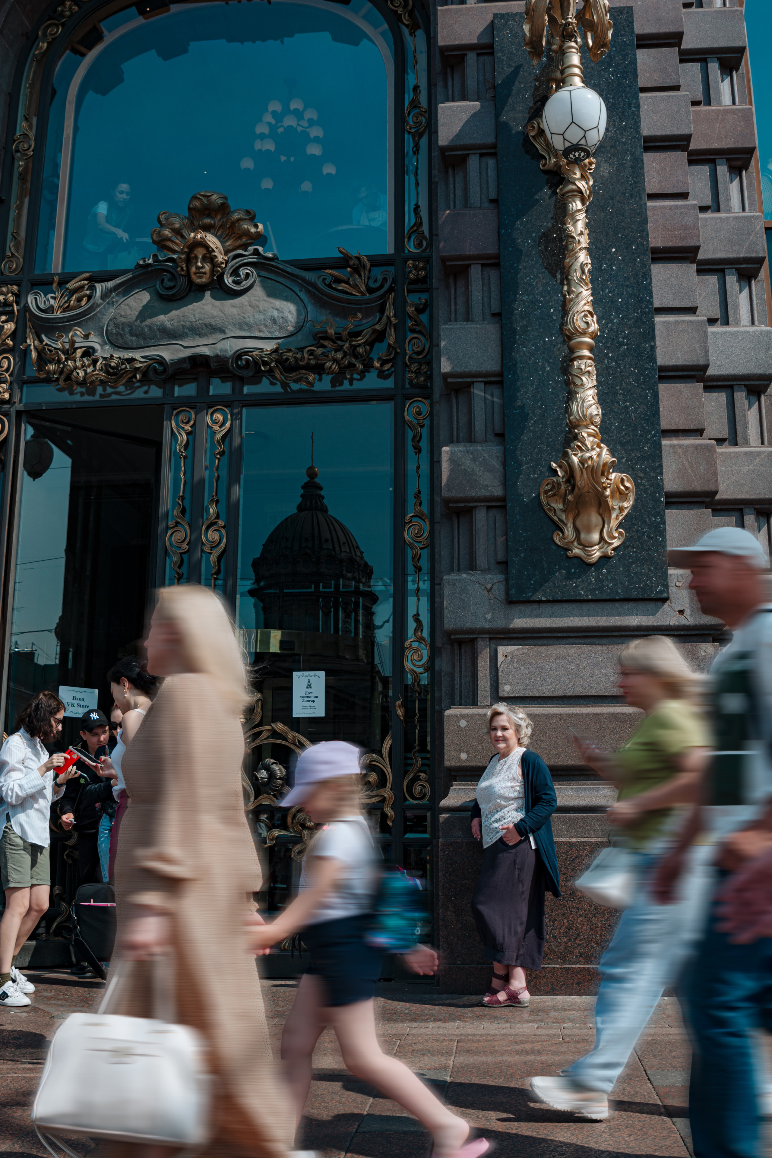 Женщина 60 лет, наслаждающаяся прогулкой возле Зингер - одного из самых известных зданий в Санкт-Петербурге.