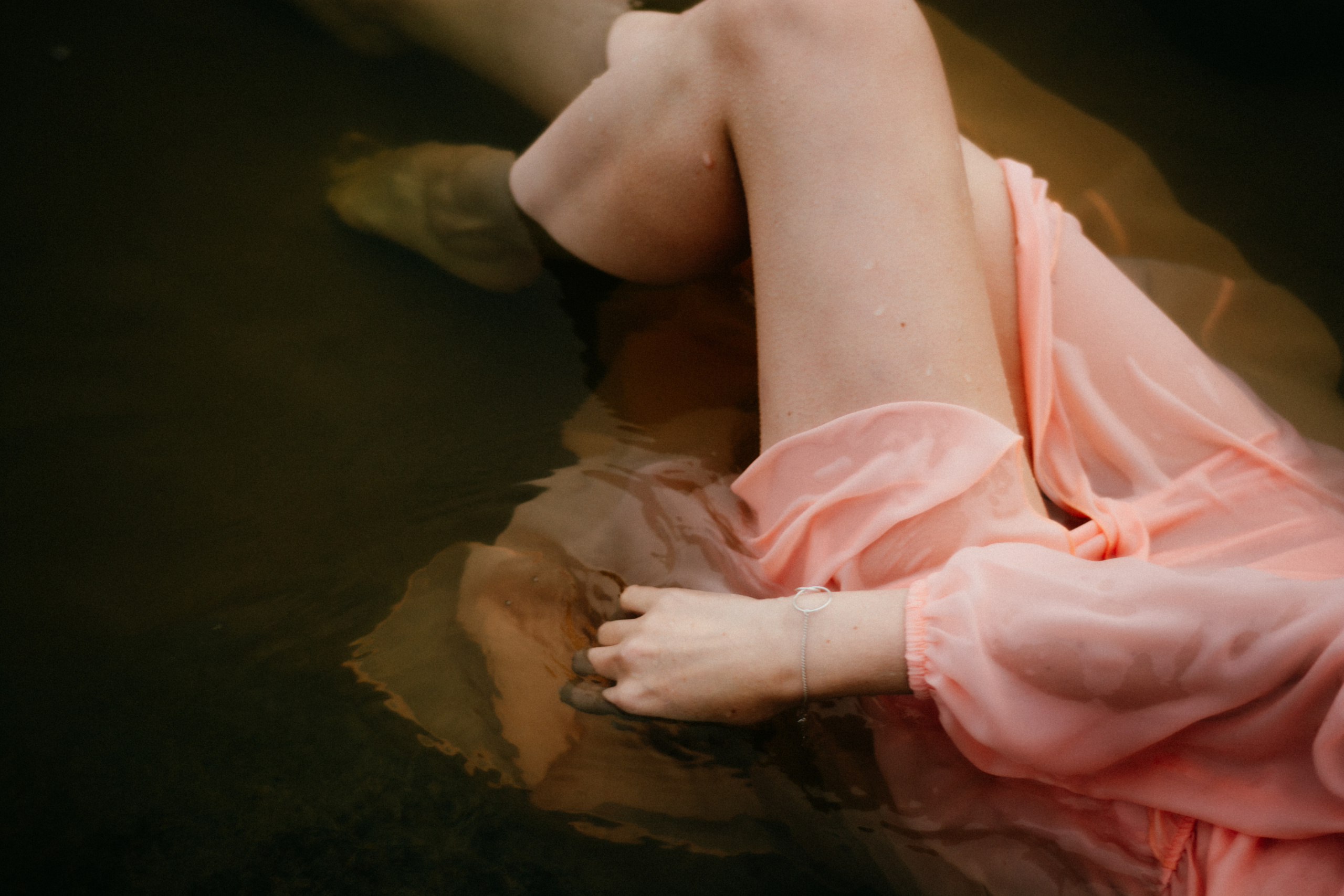  Силуэт девушки в розовом платье плывет в воде, создавая впечатление элегантности и свободы.