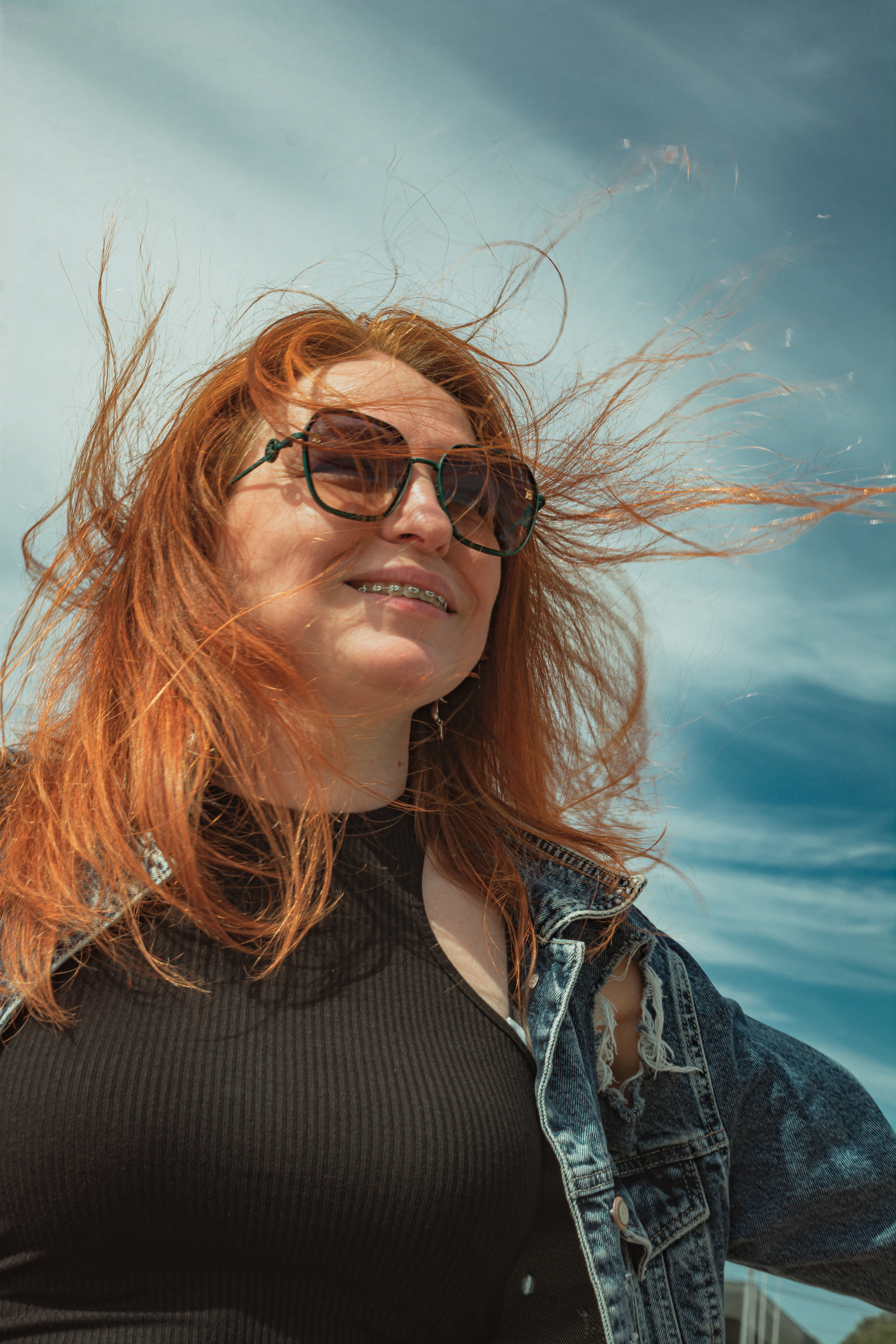 Рыжеволосая девушка с брекетами улыбка красивое небо