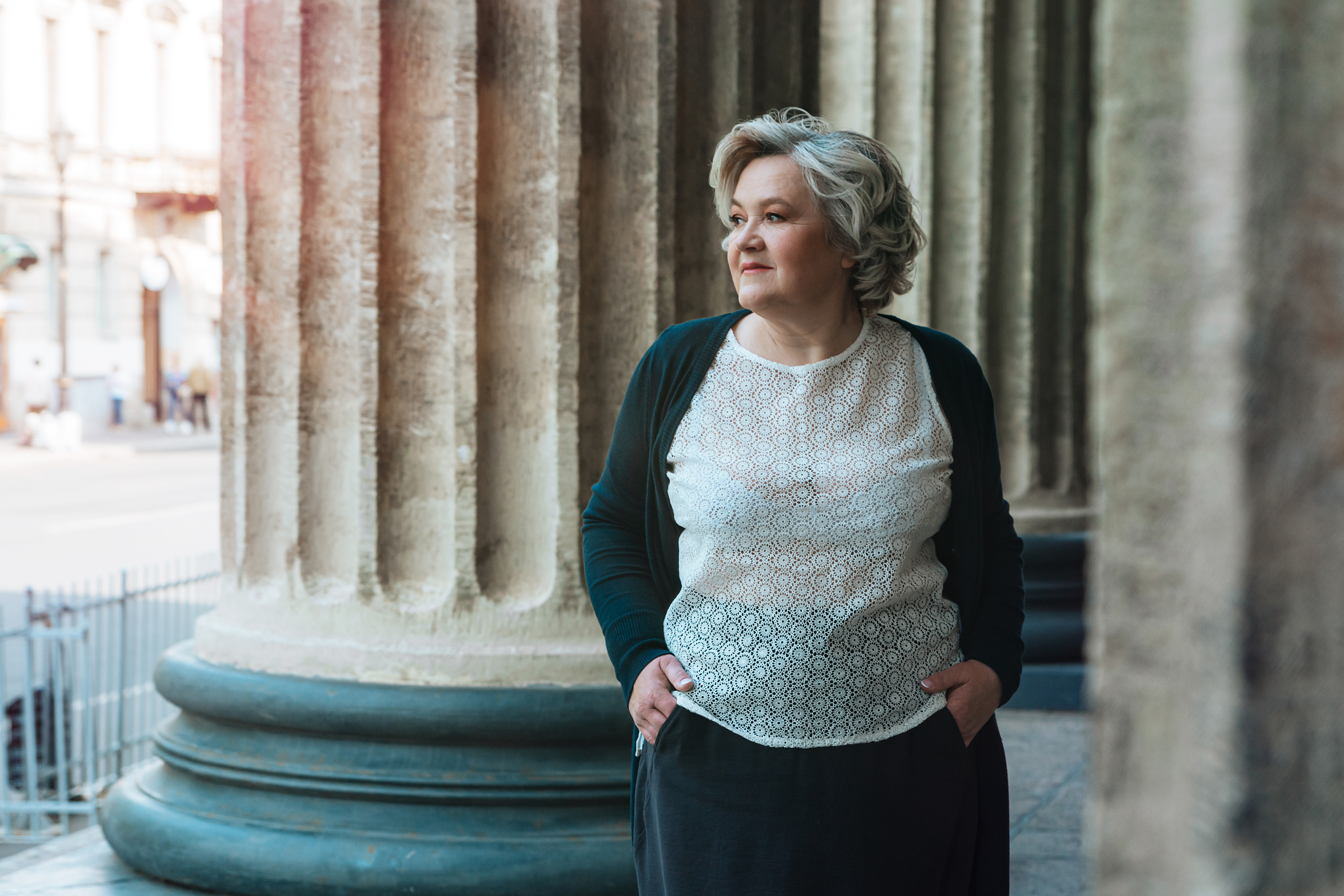 Женщина 60 лет, прогуливающаяся летним днем перед Казанским собором в Санкт-Петербурге.