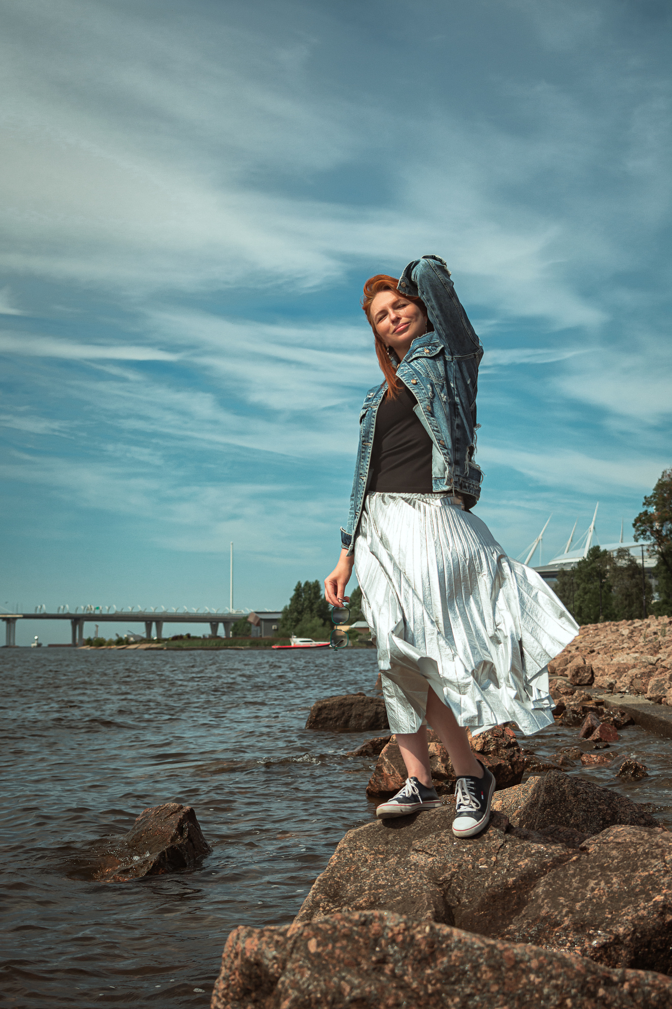 Мост на фоне, рыжеволосая девушка стоит на камнях