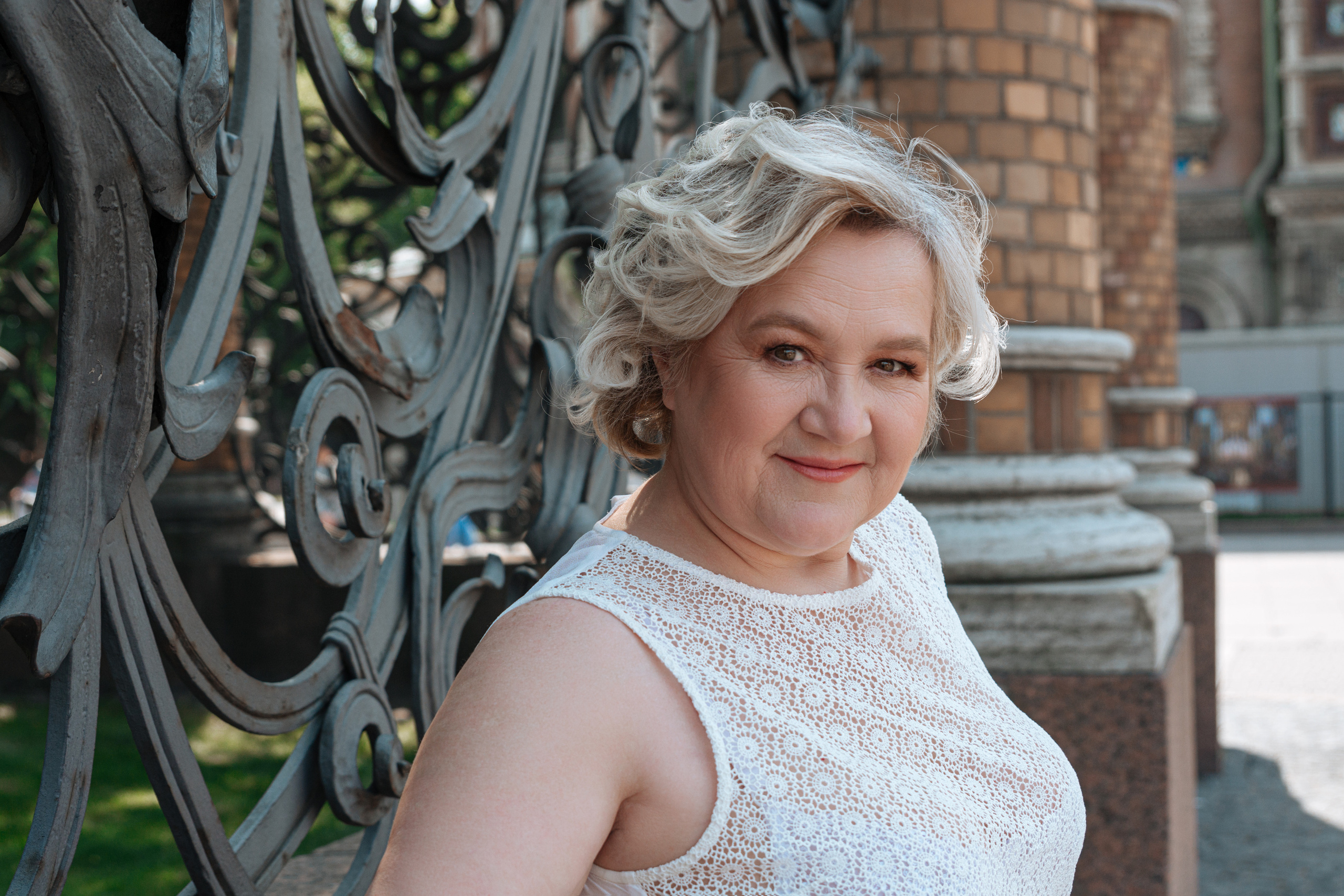 Женщина 60 лет, ощущающая величие и историю Храма Спаса на Крови, пронизывающая ее сердце во время прогулки по его территории.