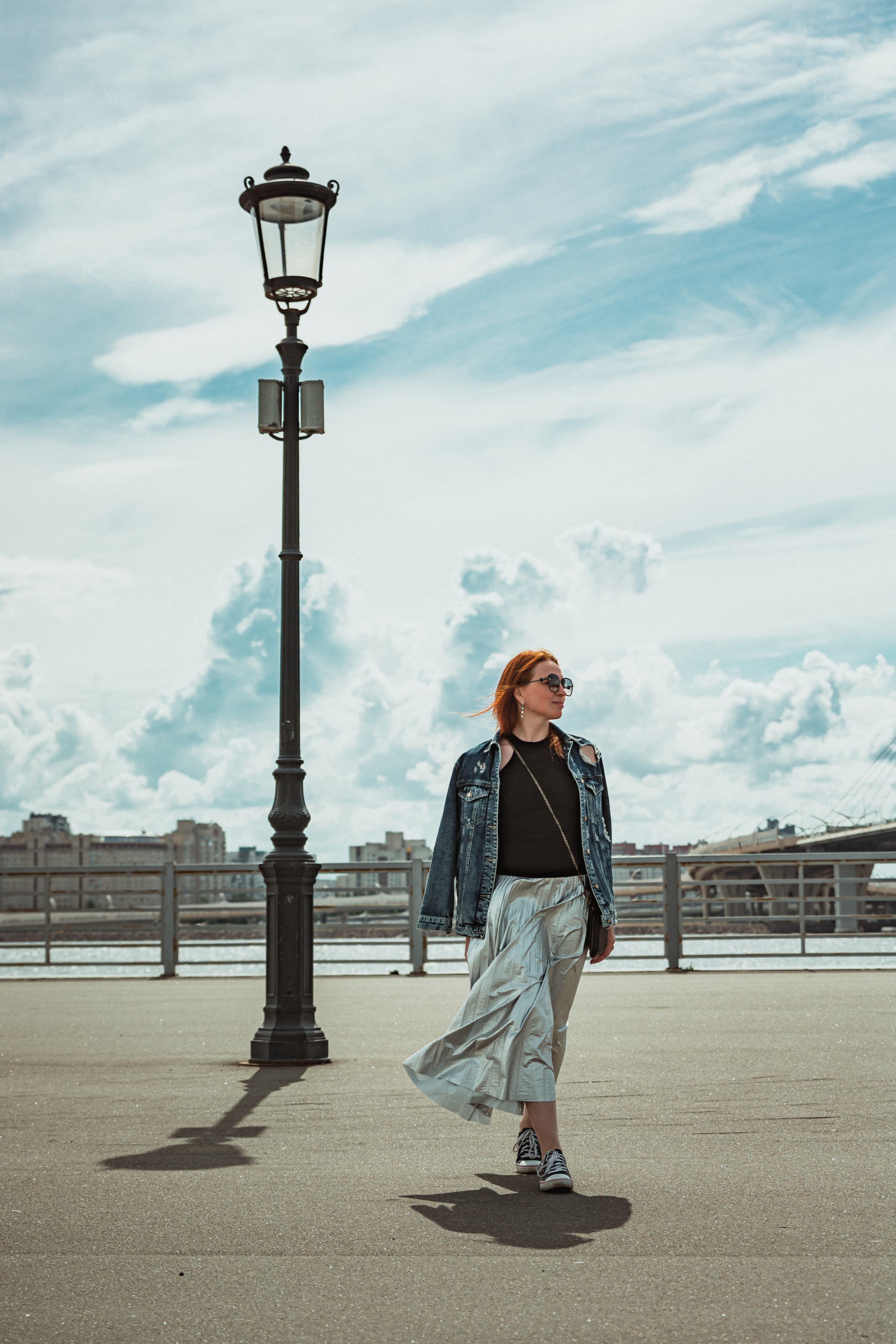 Рыжеволосая девушка рядом с фонарем на набережной