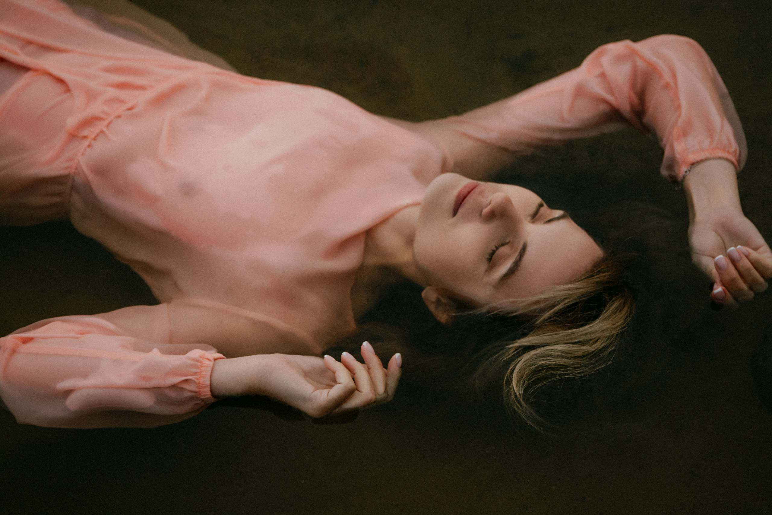  В объятиях воды лежит девушка в своем нежно-розовом платье, испытывая волнующее умиротворение.