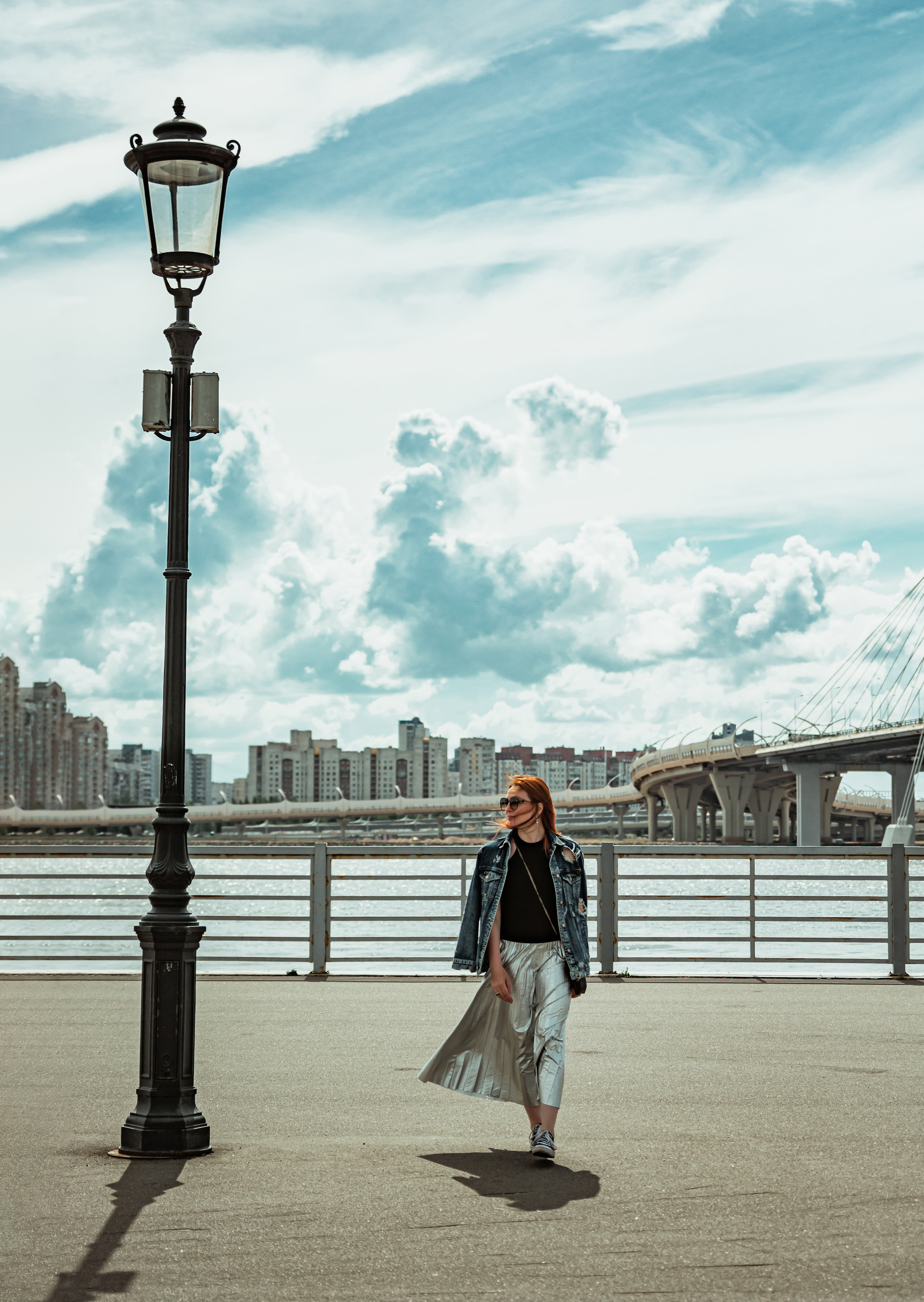 Рыжеволосая девушка рядом с фонарем на набережной