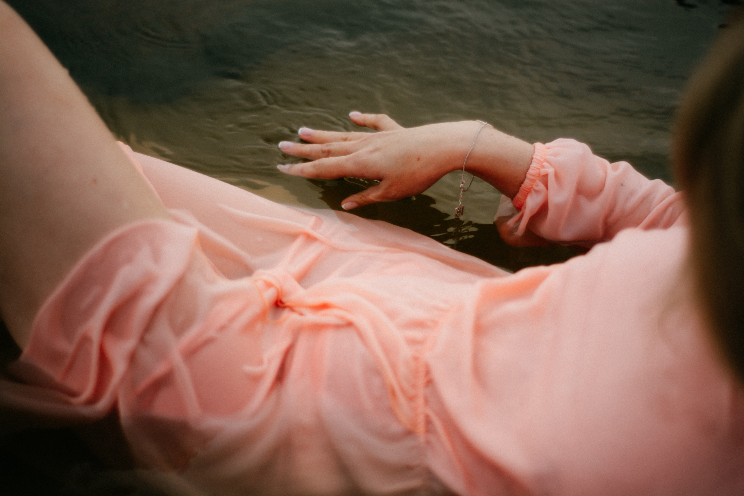 Вода нежно обнимает лежащую в ней девушку в розовом платье, принося ей покой и гармонию.