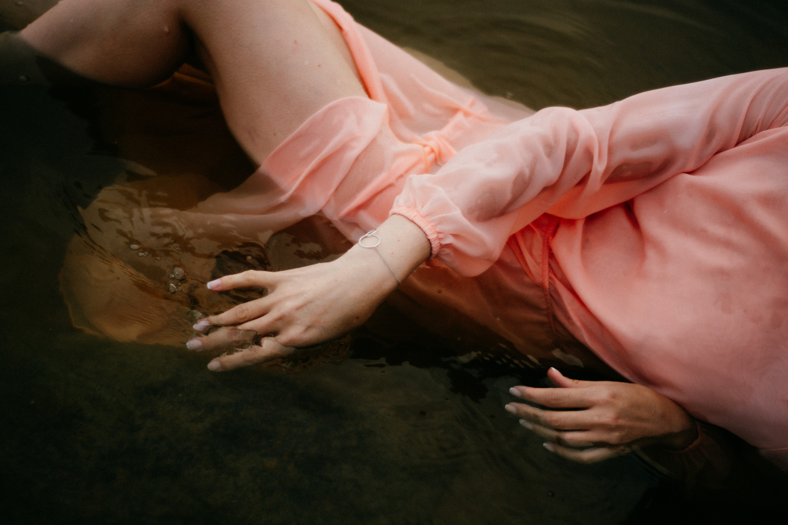 Вода обнимает девушку в розовом платье, создавая атмосферу мистической притягательности.