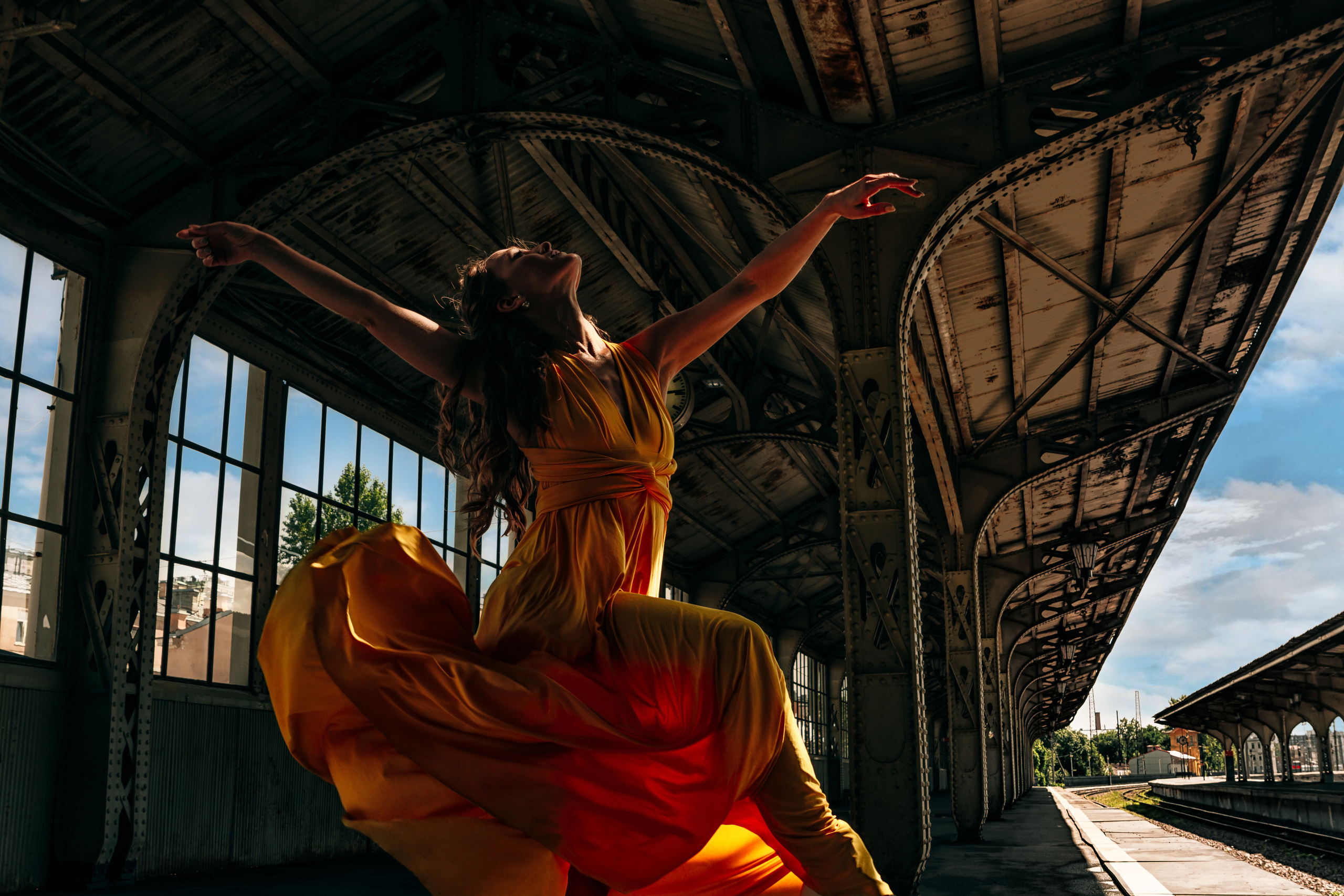 Желтое платье на танцовщице создает огненный образ, воплощая грацию и эффектность ее движений на Витебском вокзале.