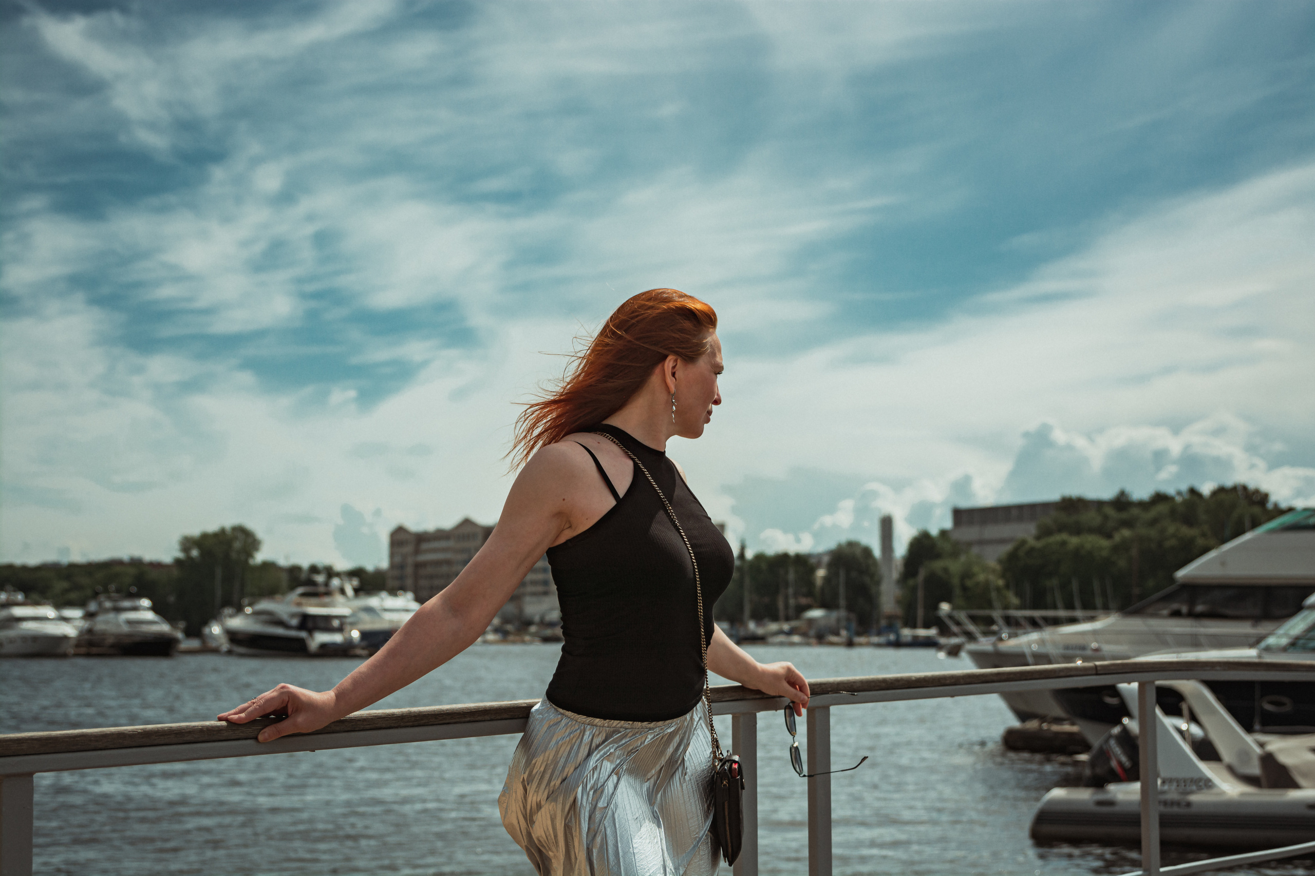 Рыжеволосая девушка стоит на пирсе