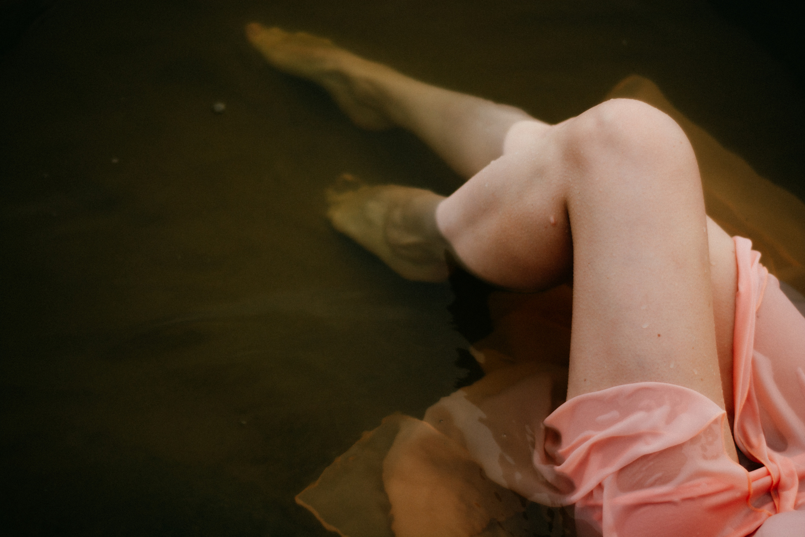  Водная гладь нежно обнимает лежащую девушку в ее легком розовом платье, создавая атмосферу безмятежности и умиротворения.