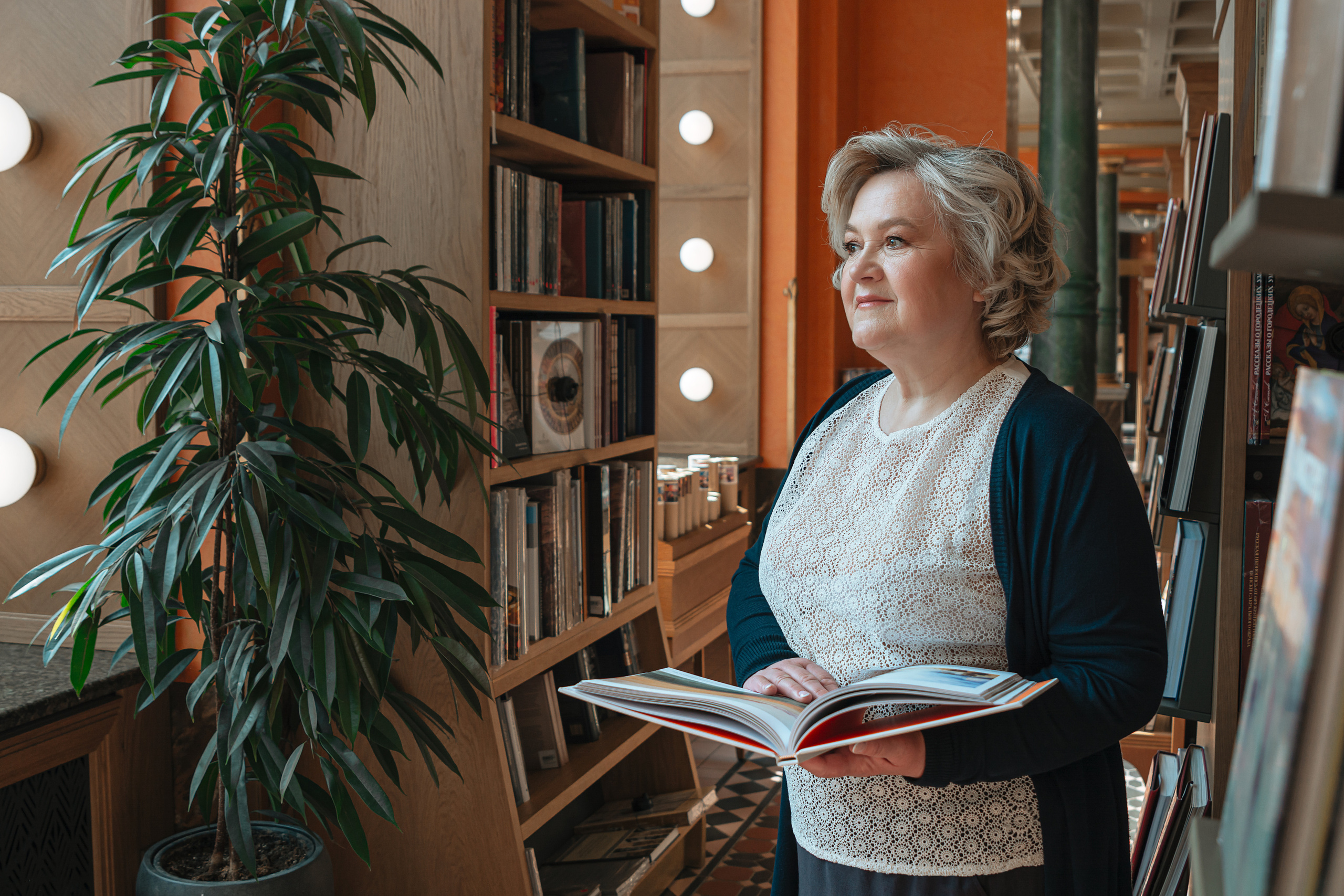 Фотография пожилой женщины, погруженной в чтение книги в Доме Зингера, символе литературной культуры Санкт-Петербурга.