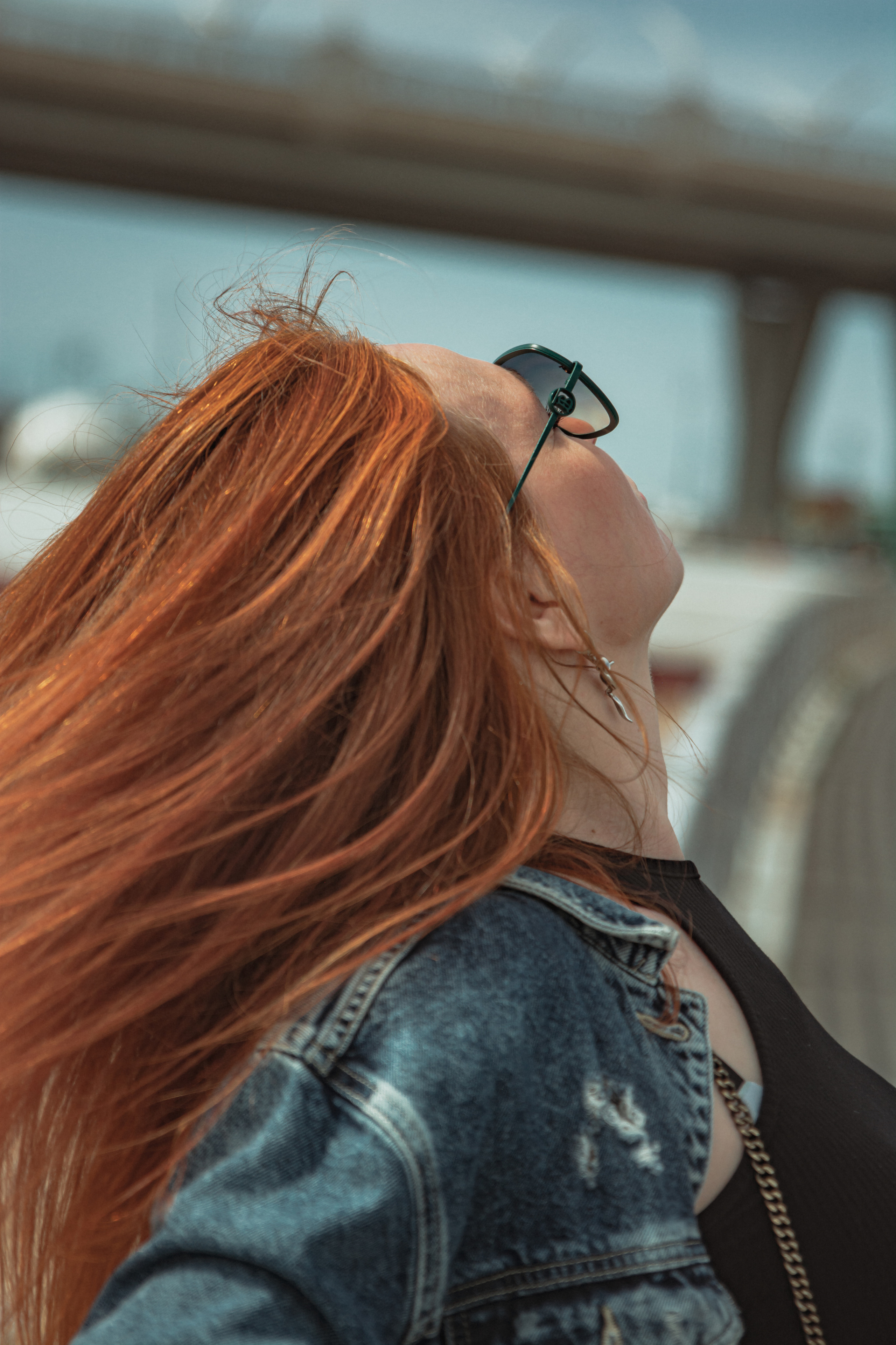 Рыжеволосая девушка у моста на набережной кайфует